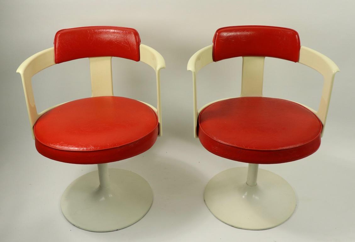 Groovy pair of swivel chairs by Daystrom. The chairs have off white frames with lipstick red vinyl backrests and seat pads, on white Saarinen style pedestal bases. Well crafted of durable materials, chic, and fun pair of chairs. Offered and priced