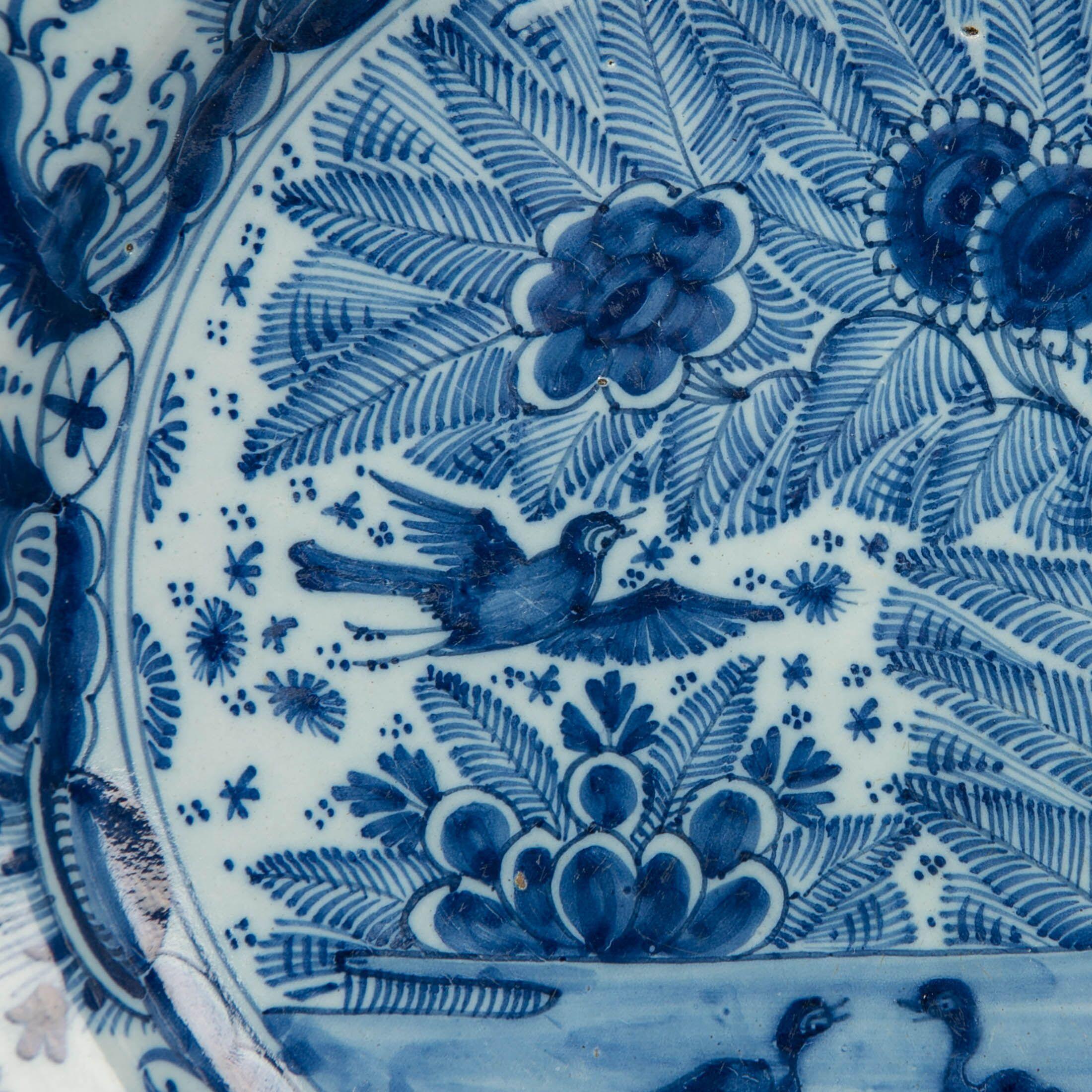 We are pleased to offer this pair of Dutch delft Blue and White chargers showing ducks on a pond and a songbird in flight placed against a naturalistic setting of ferns and sunflowers.
The ducks are adorable and seem to be talking to each other