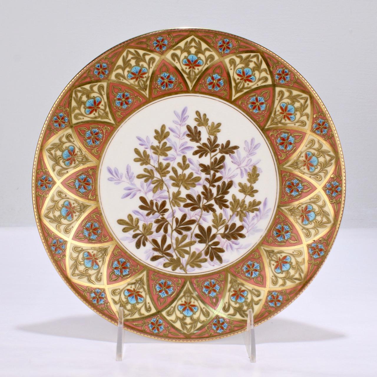 Un pari muy fino de platos de gabinete antiguos del periodo Estético dorados y esmaltados de porcelana Derby (predecesora de Royal Crown Derby).

Los platos tienen un borde de color salmón y crema con reflejos en relieve de esmalte turquesa, rojo