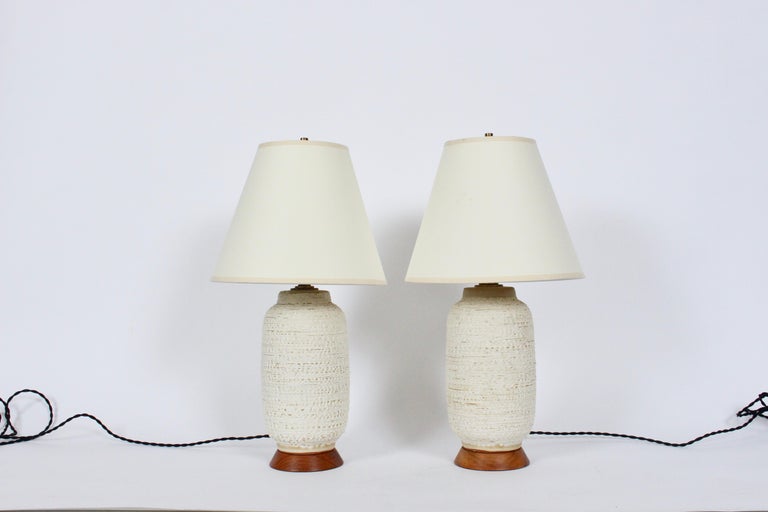 American Mid Century Modern lee rosen for Design Technics textured, glazed pottery bedside lamps. Featuring handcrafted petite and rare Design Technics forms with stipple glaze on flared Walnut bases. 
13H to top of sockets. 10H to top of bases.