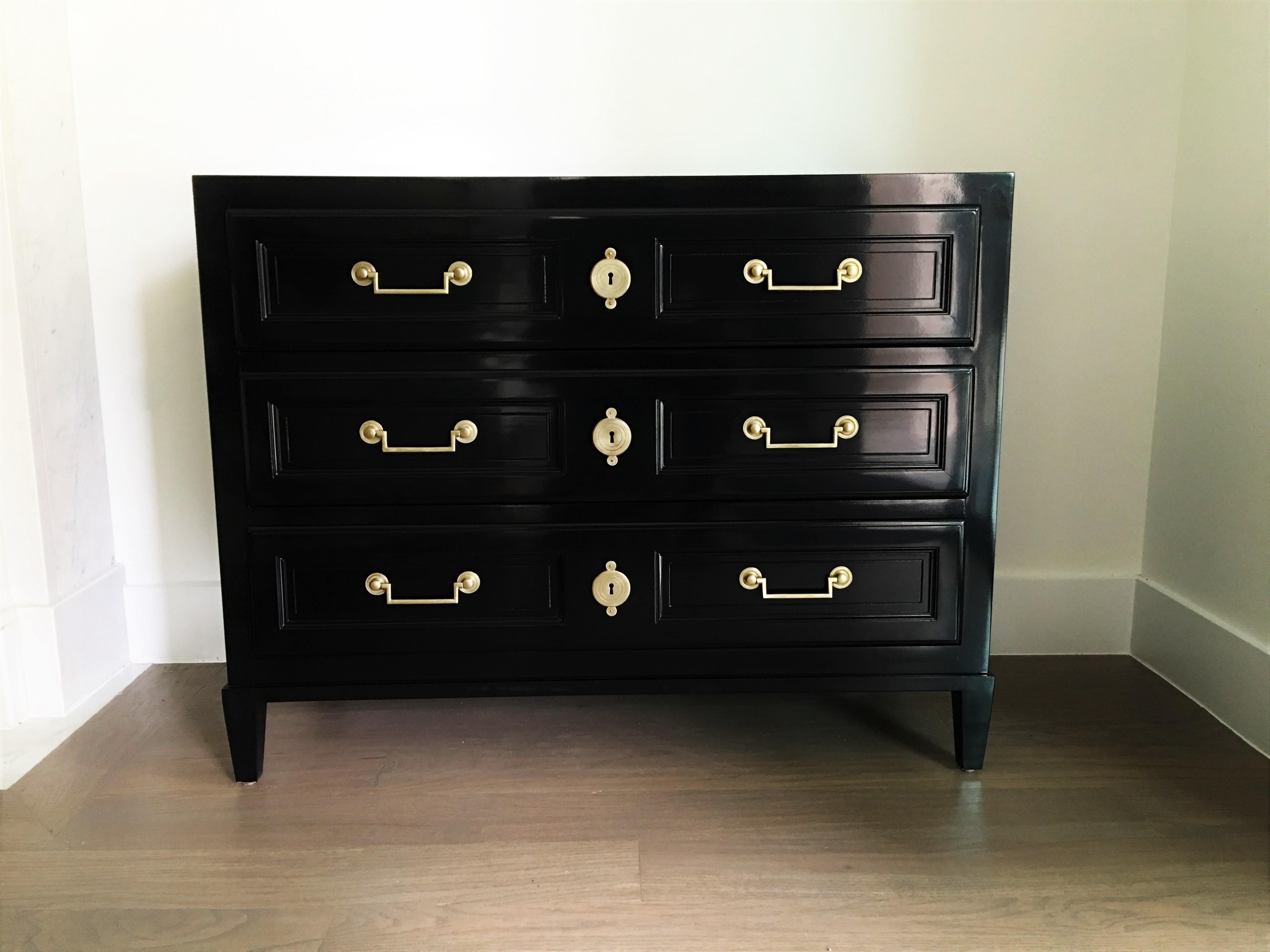 Stunning pair of Directoire style commodes/chest of drawers by Baker Furniture. Newly refinished in black lacquer. Solid wood construction each consisting of three dovetailed drawers with unique, gilt bronze hardware. Baker tag in corner inside top