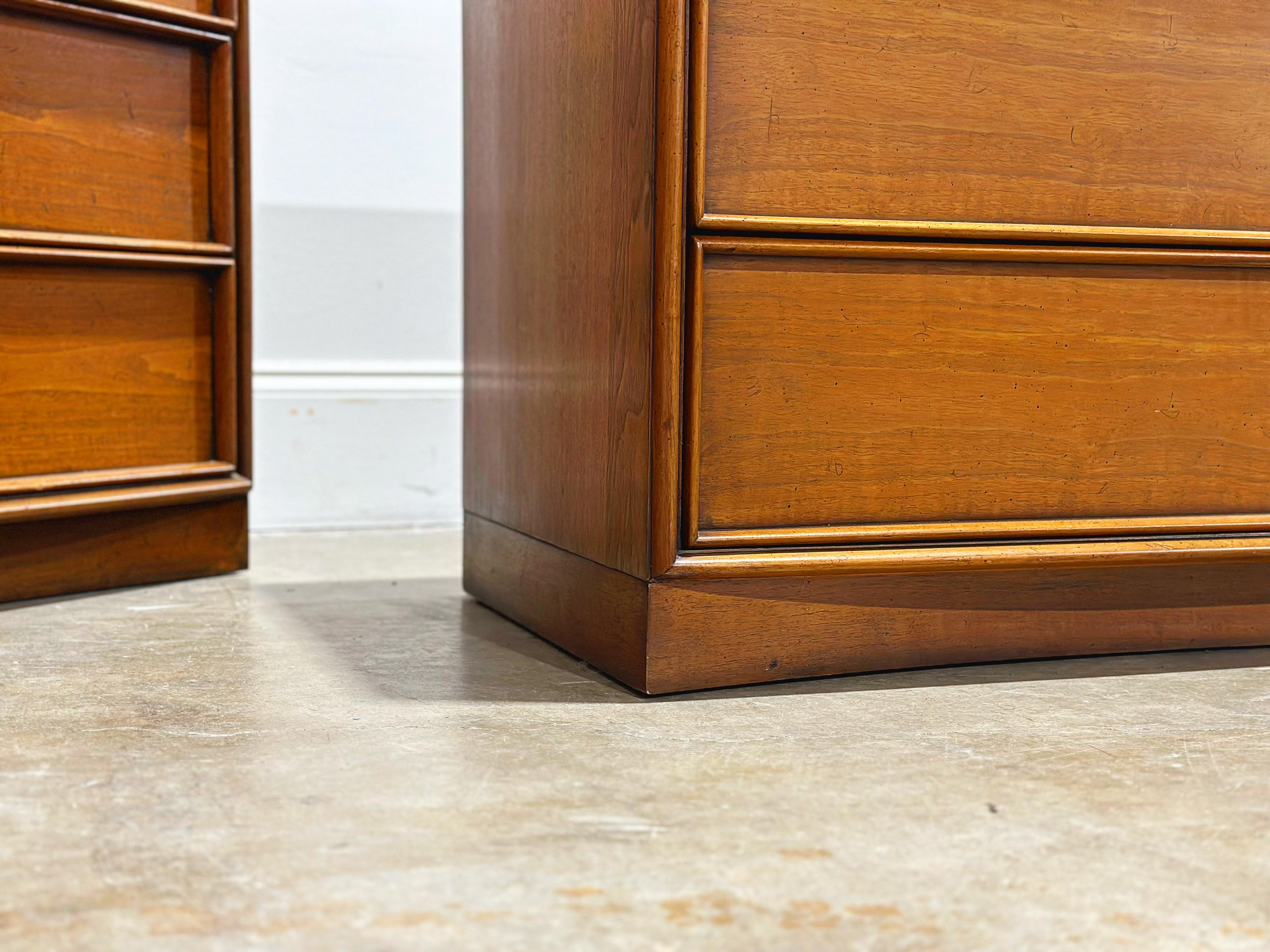 Scarce pair of walnut bachelors chests / nightstands / dressers by TH Robsjohn Gibbings for Widdicomb, circa late 1950s. Three drawers resting on Gibbings' signature curved plinth base. Gorgeous medium tone walnut, stellar understated design and top