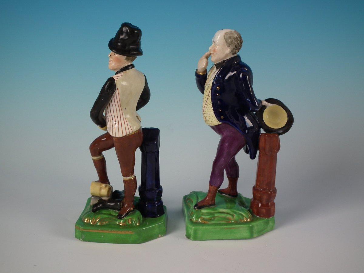 Pair of Staffordshire Pottery figures with a theatrical and literary theme which feature two gentleman, stood on a square base. Dull gilt base line and embellishment. Decorated 'in the round' - decoration to front and reverse. This piece represents