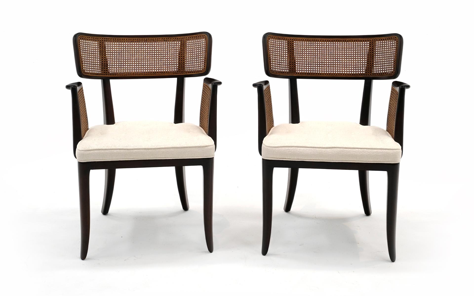 Two sculptural dining chairs / occasional chairs with arms designed by Edward Wormley for Dunbar. These have been expertly refinished and reupholstered in an off white boucle fabric. No holes or damage to the cane. The frames may show a few signs of