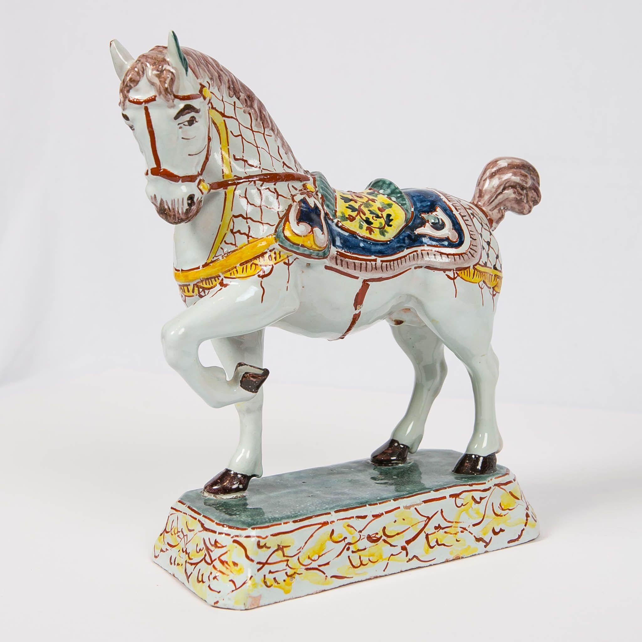 We are excited to offer this outstanding pair of Dutch Delft horses. Modeled looking to the side, they are prancing with one leg raised. Each horse is painted with a white coat, a caparison covering of iron red and midnight brown mesh. They have