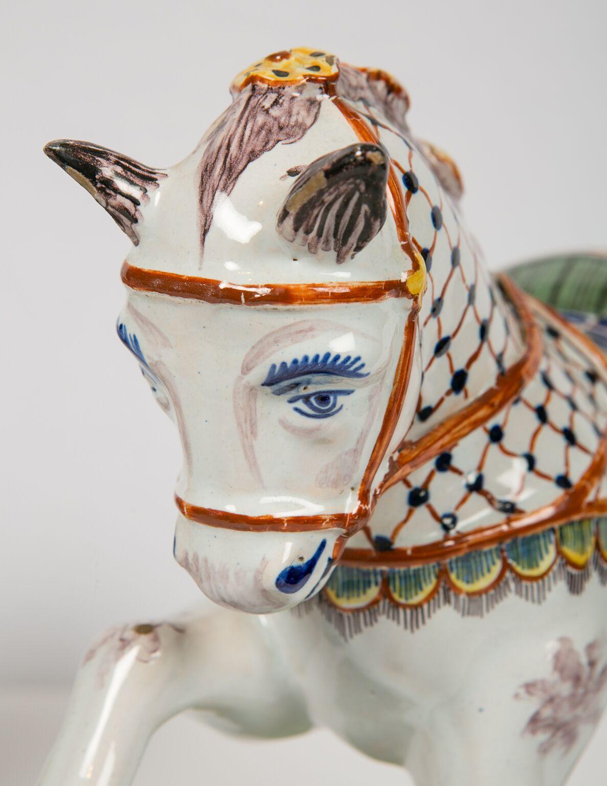 We are excited to offer this outstanding pair of Dutch Delft horses. Each horse is painted with a white coat, a caparison covering of iron red and blue mesh, brown ears, hooves, forelock and tail, blue eyes and mouth. Each horse is wearing garlands