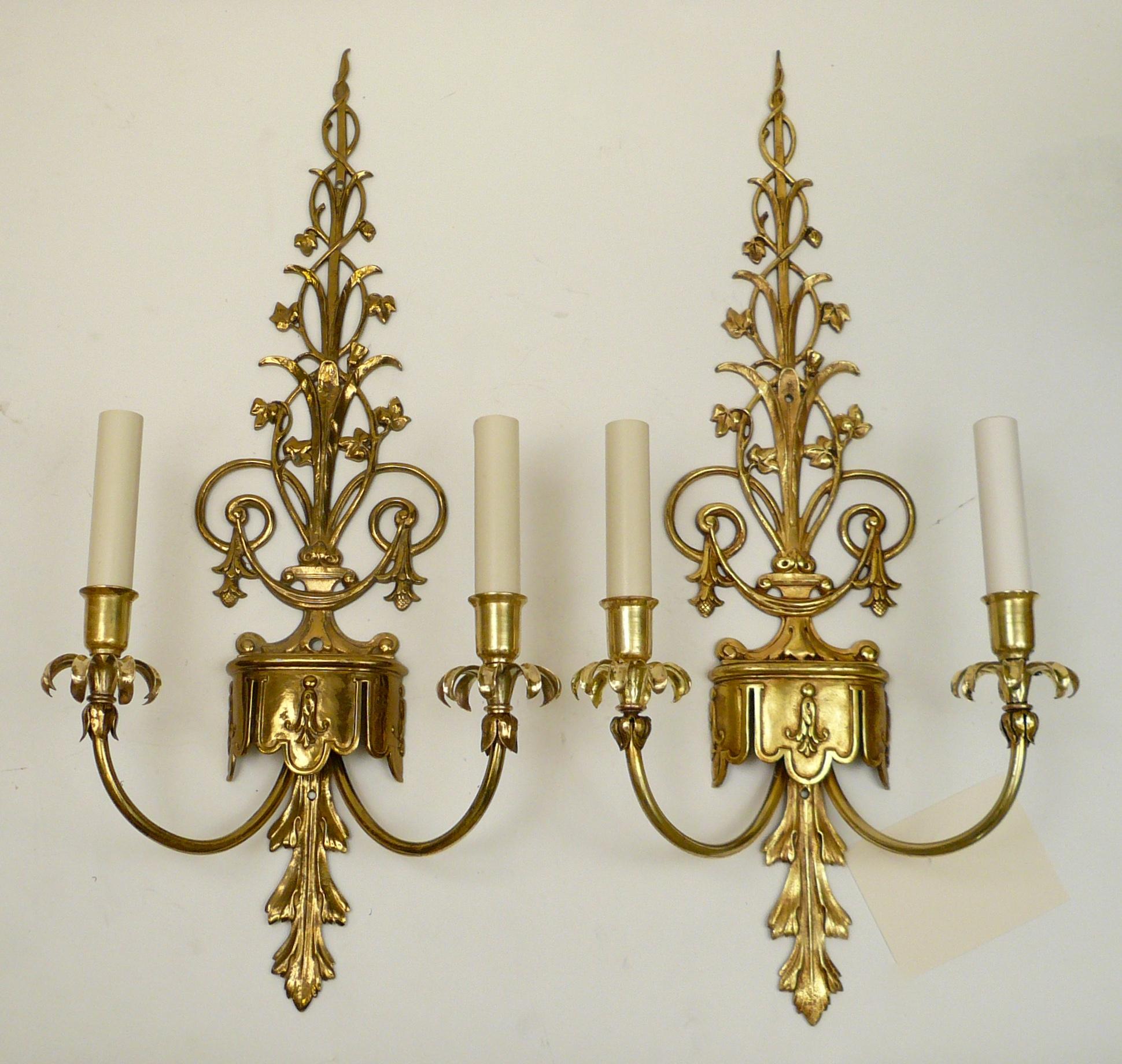This handsome pair of cast and burnished brass sconces feature Robert Adam style neoclassical motifs including acanthus leaves, and bellflowers.