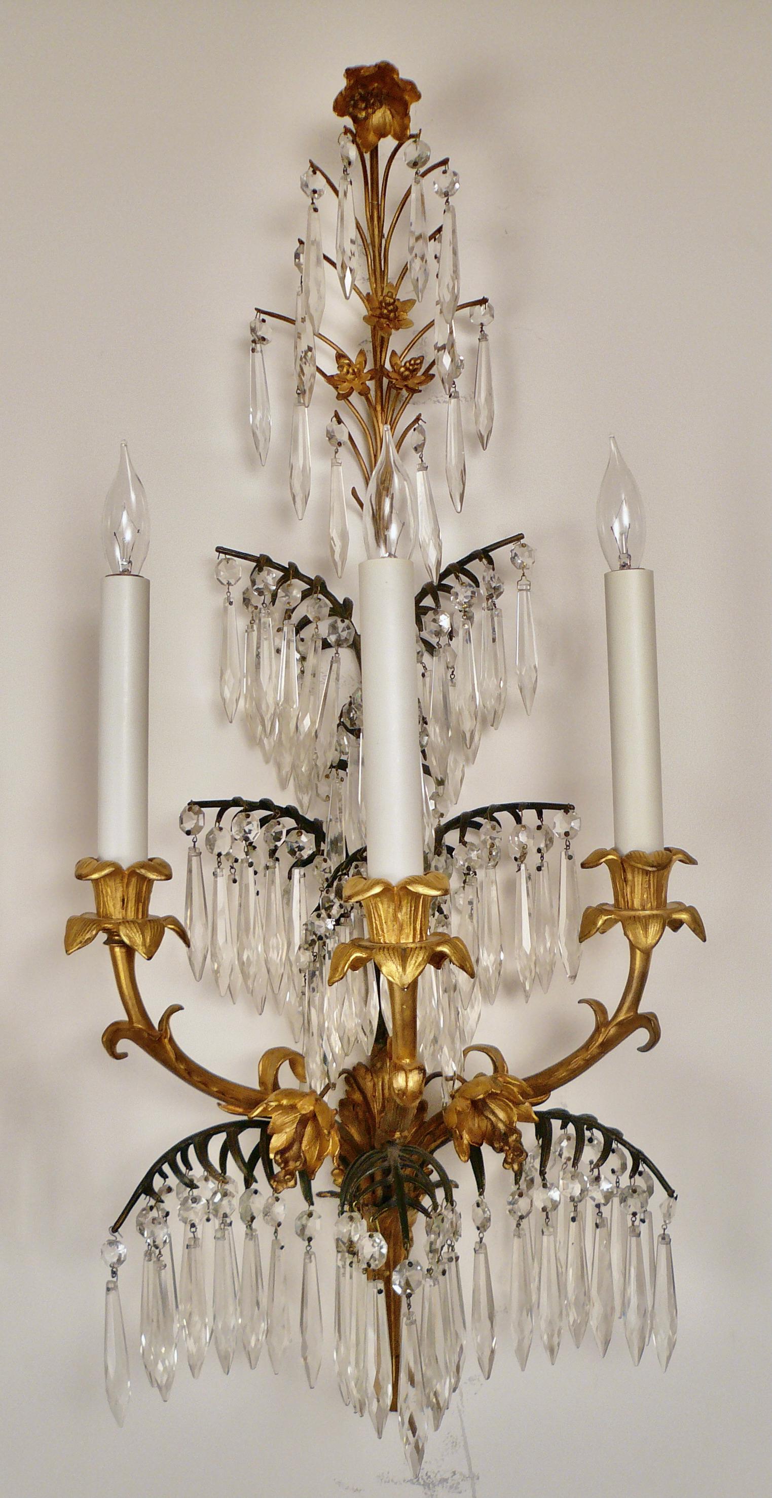 This amazing pair of gilt and patinated bronze sconces by Caldwell feature palm leaves, gilt bronze flowers, and lily form candle cups.
