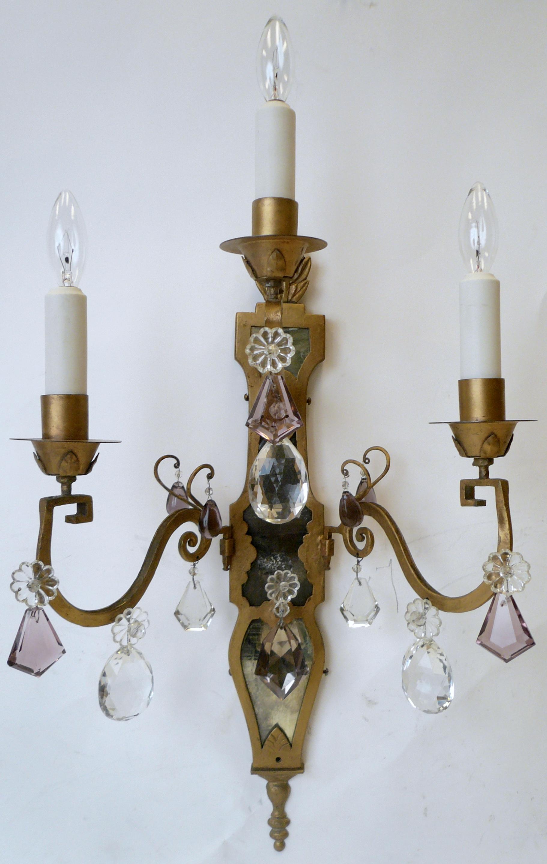 This handmade pair of three-light Continental style sconces feature antique mirrored backs, and gilt flame form finials.