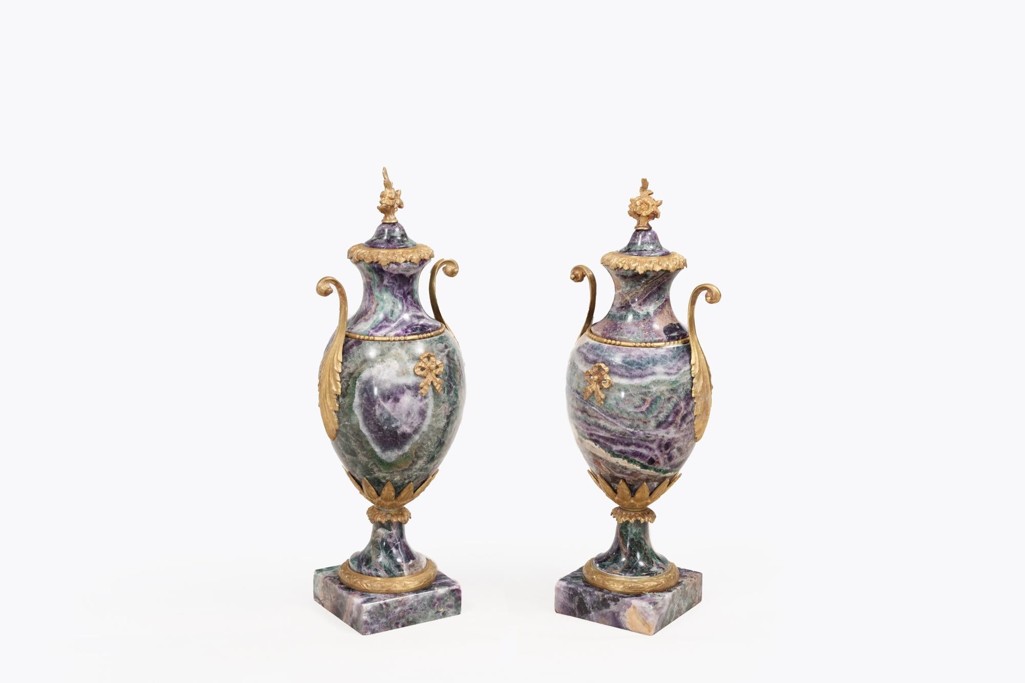 Pair early 19th Century Blue John cassolettes with ormolu mounts each with an ovoid body applied with decorative mounts and scrolling foliate handles, beneath a removable cover topped with foliate finials. The pair sit on a waisted laurel decorated