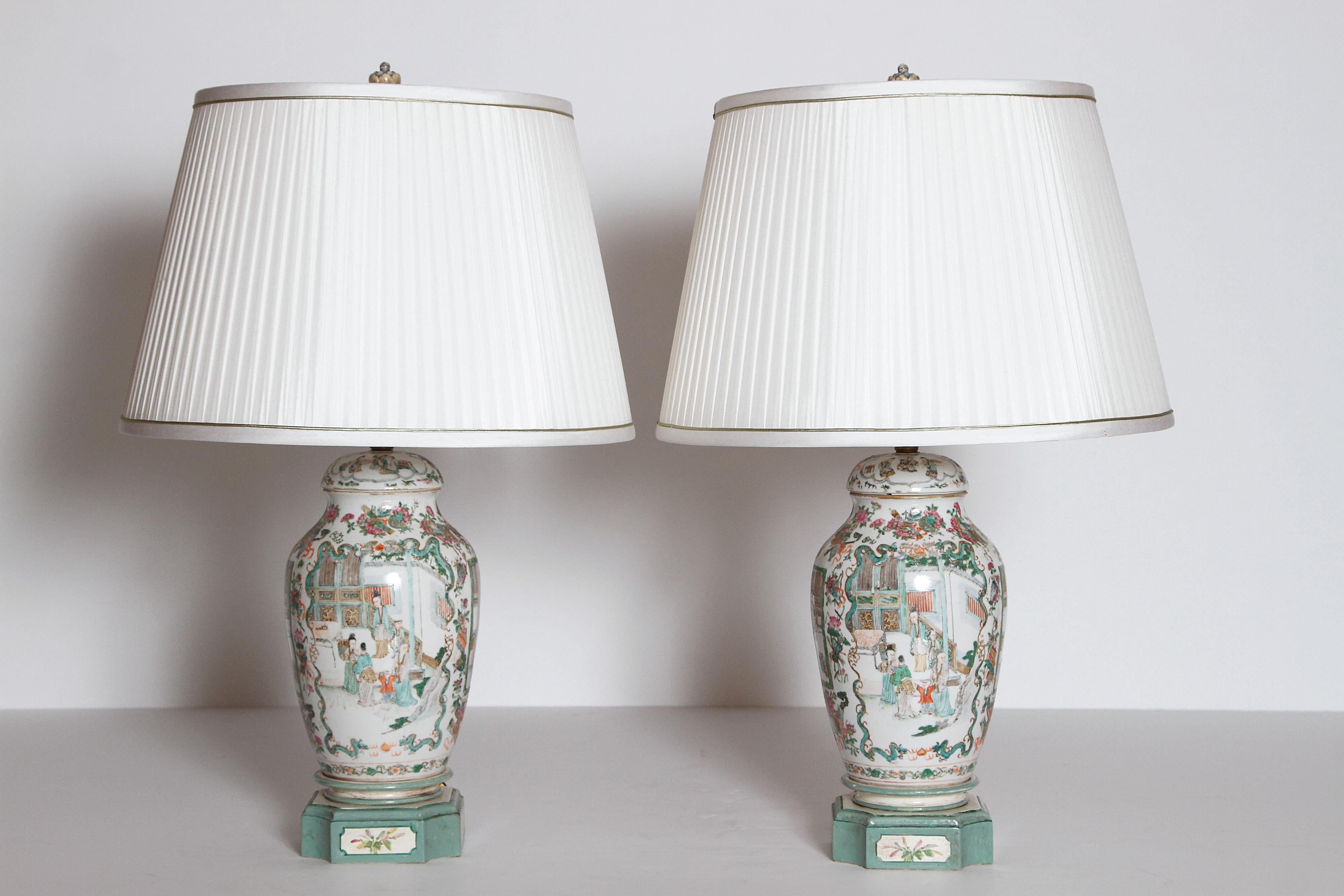 A pair of Chinese porcelain lidded jars as lamps, white porcelain with green and orange coloration. People and flowers in cartouches. Bases are painted to complement the vases, early 19th century, China.

With custom pleated shades with