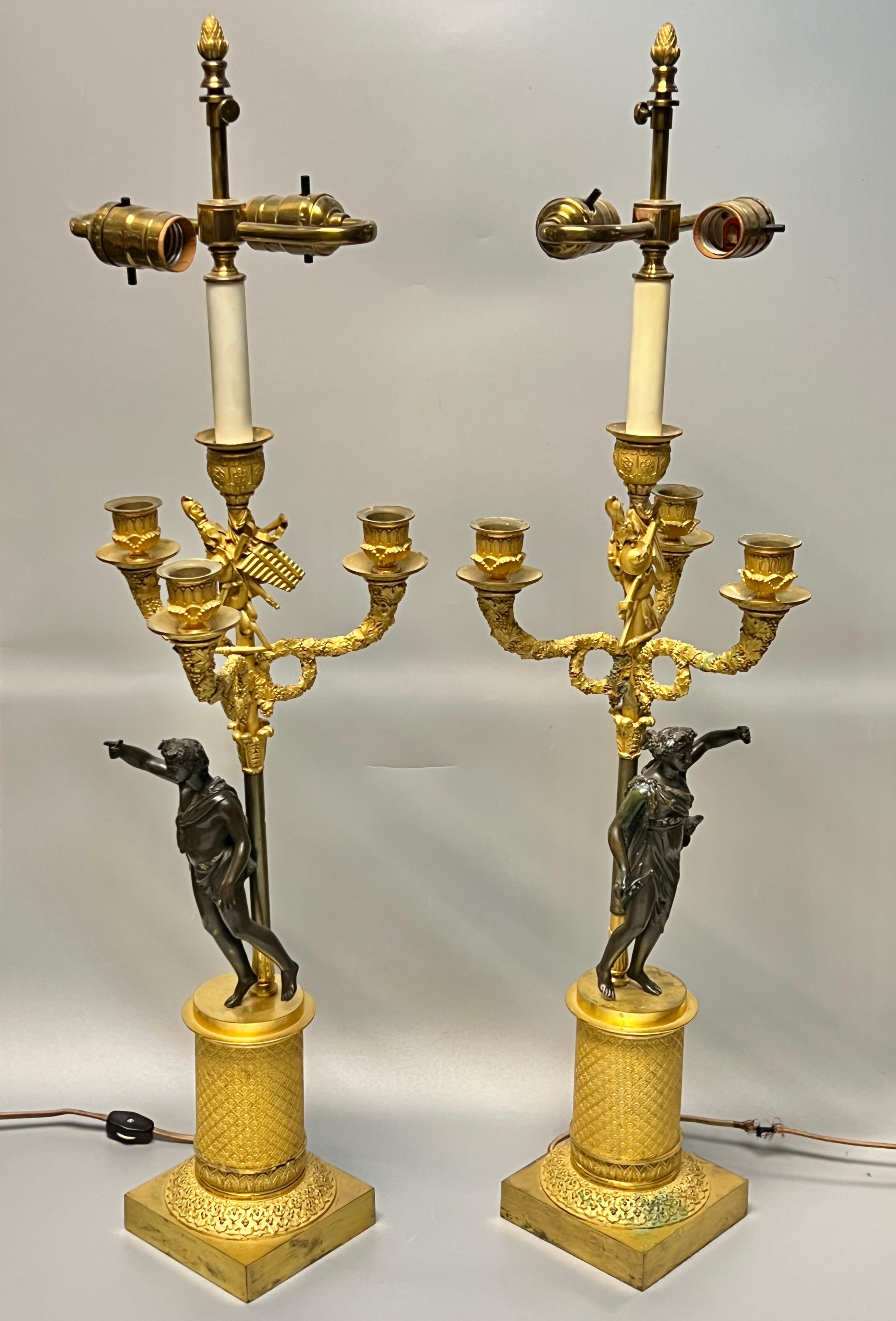Pair of antique (19th century) French candelabra of the highest quality depicting neoclassical male and female figures adorned in lion pelts with exceptional ormolu designs including berry vine wreaths and court jester with various musical