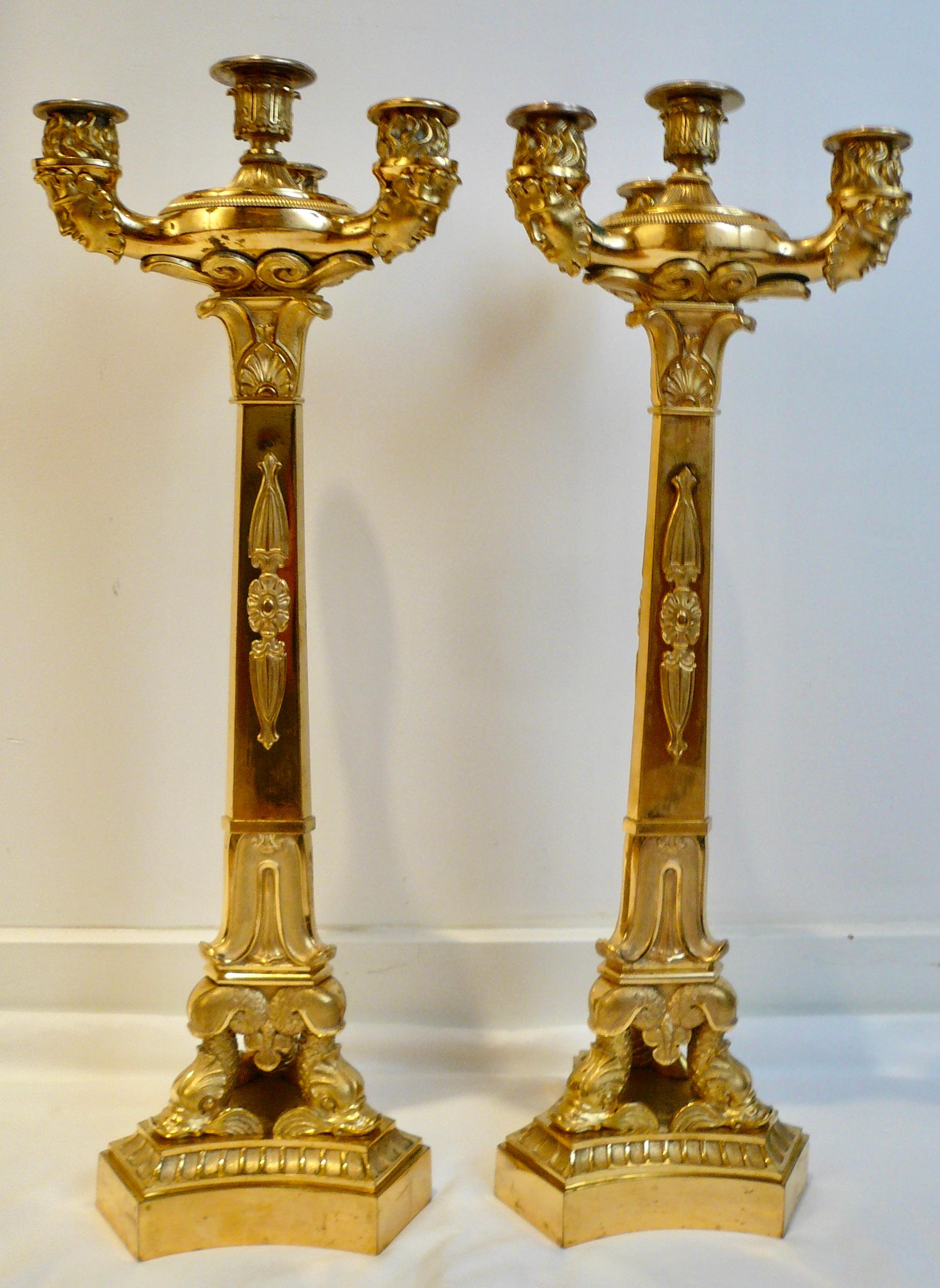 This impressive pair of Classical gilt bronze candelabra in the manner of Pierre Philippe Thomire, are beautifully made in cast bronze and have hand chased details. They feature dolphins on triangular plinth form bases supporting tapering columns.