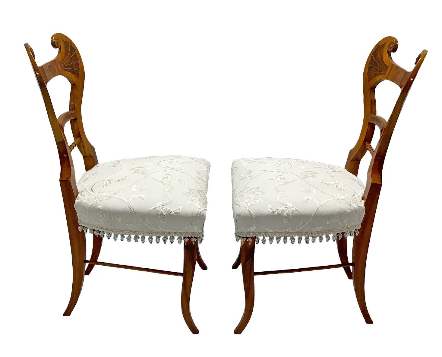 Pair of early 19th century neoclassical Biedermeier side chairs with walnut inlays, circa 1825 from Austria. These stunning chairs have been recently reupholstered with Colefax and Fowler’s ivory embroidered fabric.  The glass bead trim is from