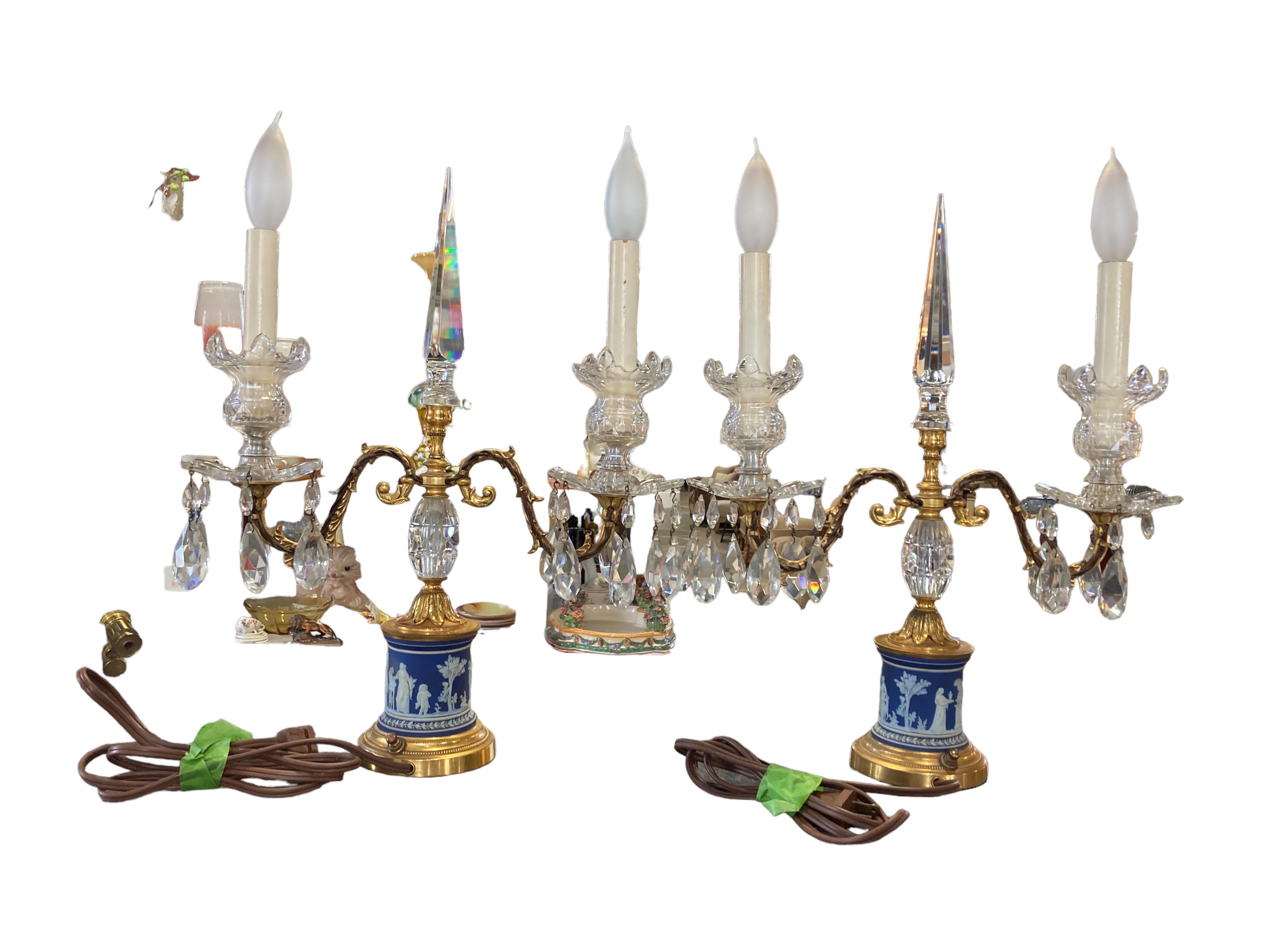 This elegant pair of lighted candelabras is comprised of Wedgwood porcelain, brass and crystal. The crystal spear at each center shines in a prism of colors in the light. The brass is in very good condition overall, as shown. There is one minor flea