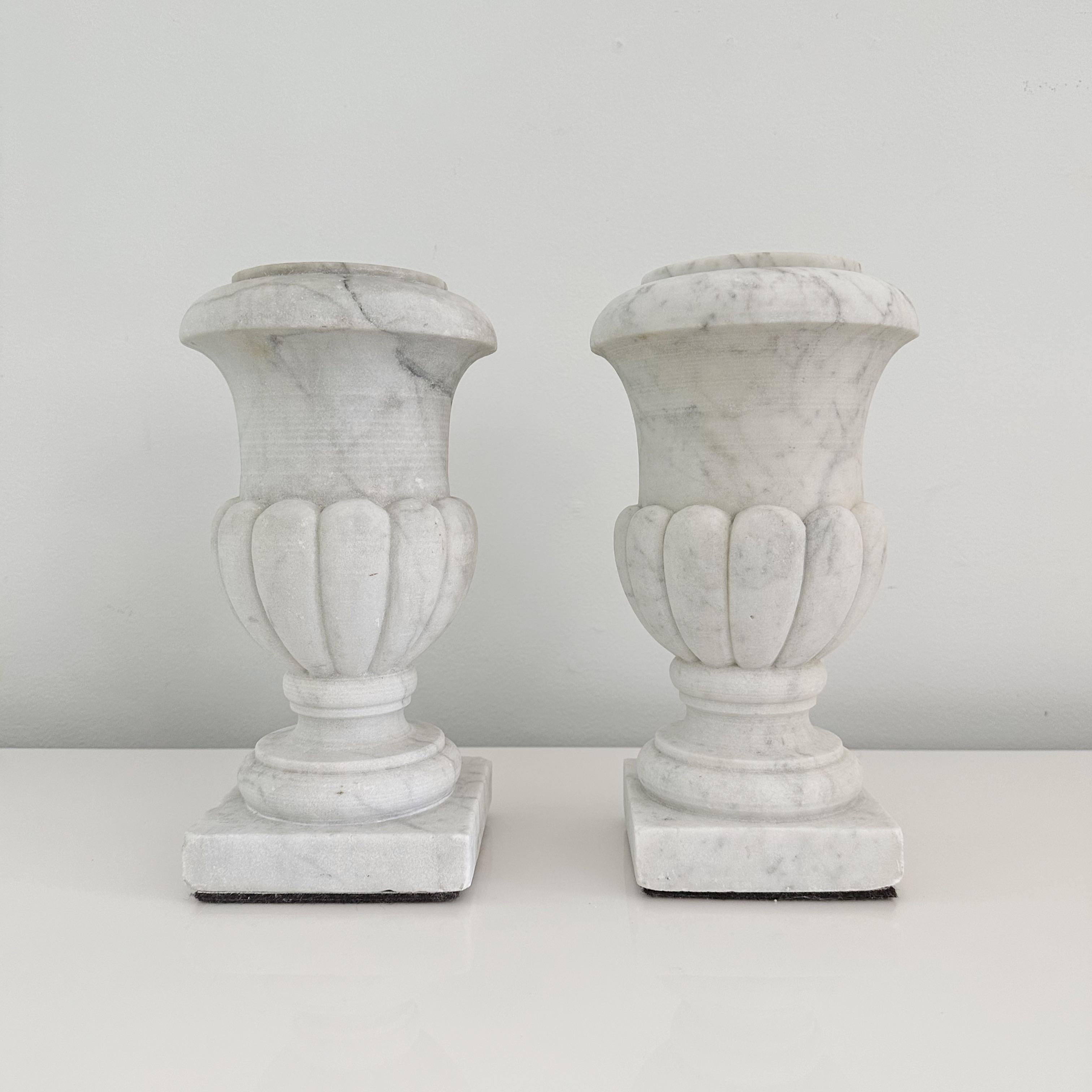 Elegant pair of hand-carved Carrara marble miniature urns, available for sale. These stunning pieces, standing at a modest height of only 12 inches, exude the grandeur and grace of the neoclassical style. Believed to originate from early