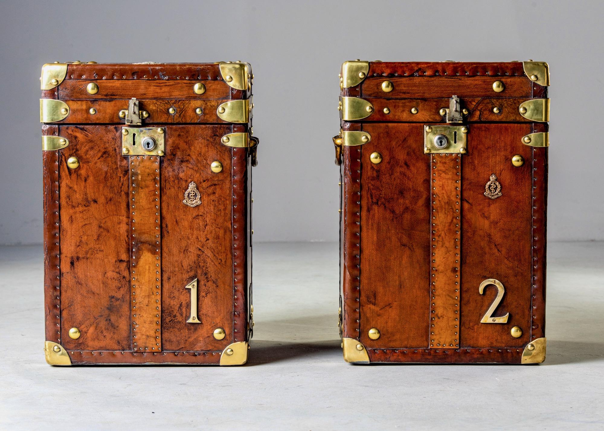 Found in England, this pair of circa 1900s pair of leather and brass trunks have been professionally restored, early 20th century. Leather has been reconditioned and patched where needed. Interiors have been recovered in a royal blue velour and the