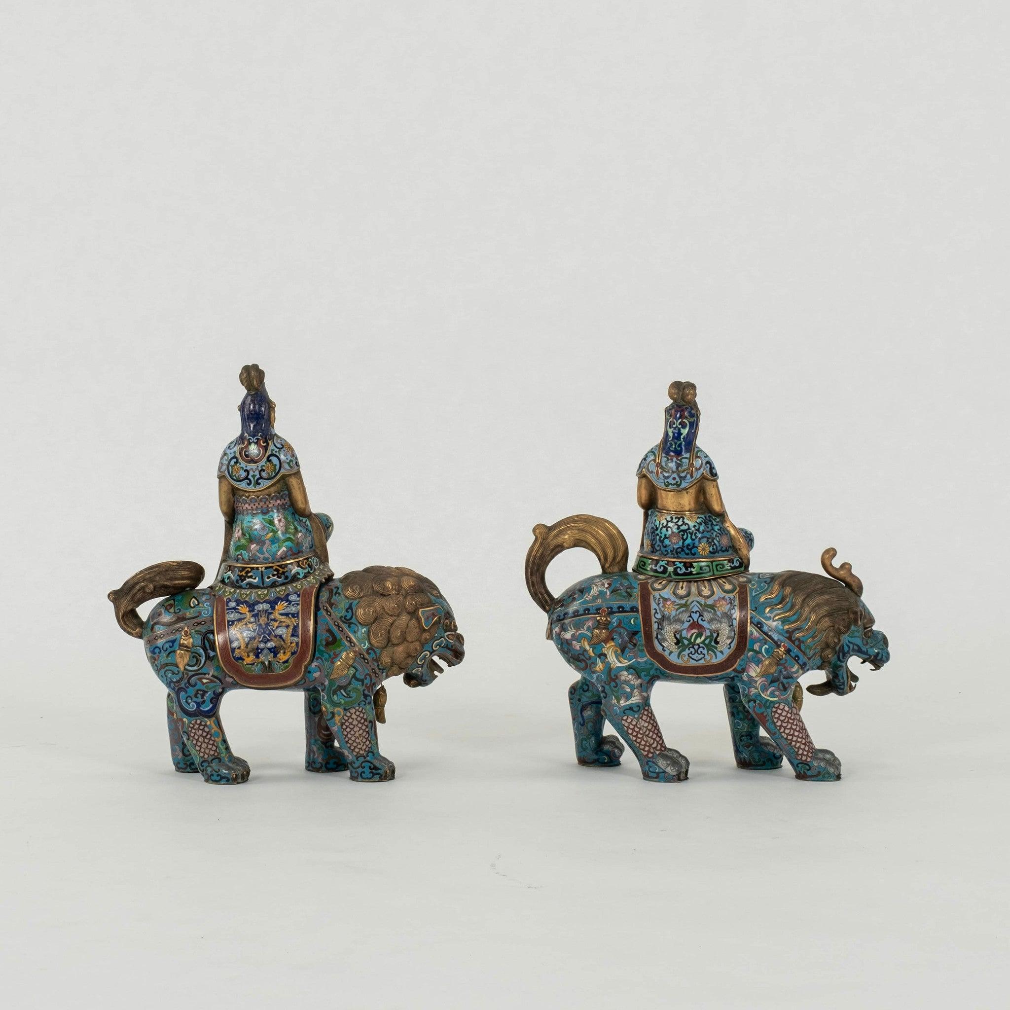Coppia di cani imperatrice Fu cloisonné. Ciascuna figura è raffigurata seduta in cima a una bestia mitica, una tiene un vaso fiorito e l'altra uno scettro ruyi, decorati con disegni dai colori vivaci di fogliame che scorre e motivi arcaici.
