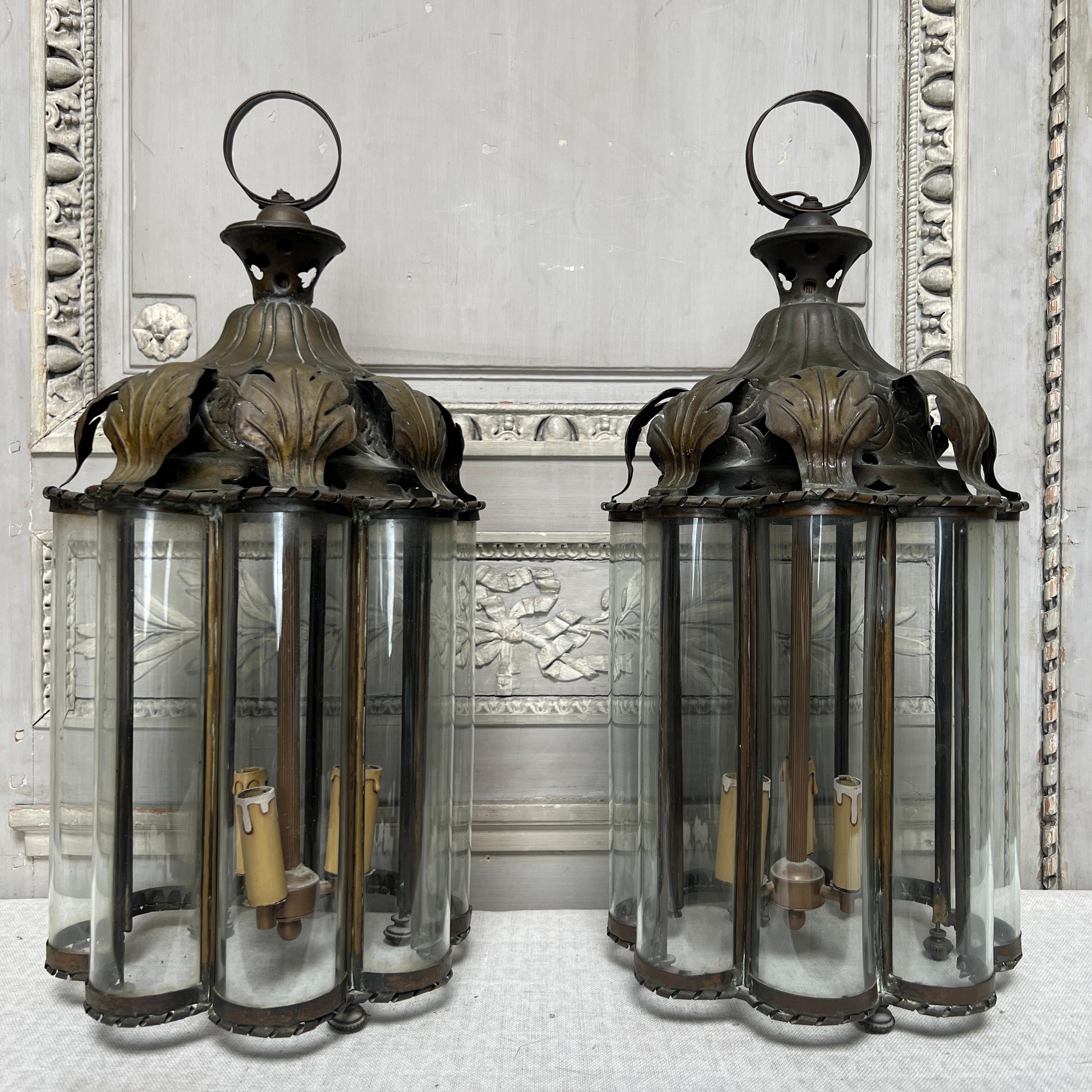 A very unusual pair of French brass and glass lanterns from the early 20th century. These lanterns are made of repousse and hammered, brass or bronze with gadrooning and acanthus leaves. This metal work is housing eight semicircular vertical glass