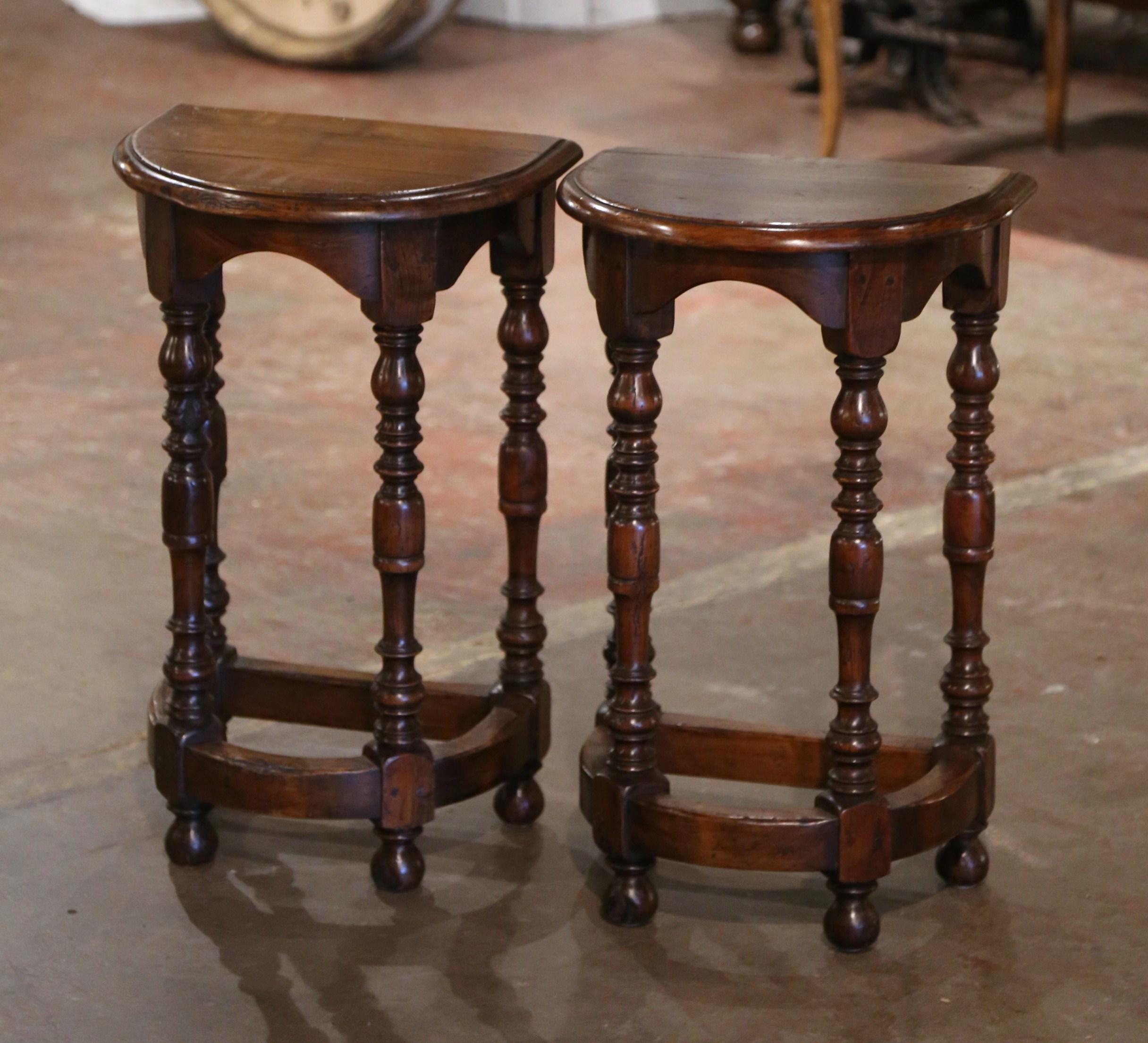 These elegant antique demilune side tables were created in France circa 1920. Built of oak, each table stands on four turned legs ending with bun feet, and connected with a sturdy stretcher at the bottom. The surface is dressed with a half moon