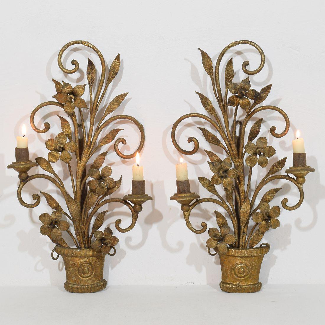 Beautiful pair of hand forged iron wall candle holders/ Sconses. Decorated with flowers and leaves.
France circa 1900-1930. Weathered, small losses and old repairs.  H:46cm  W:26cm D:10,5cm 