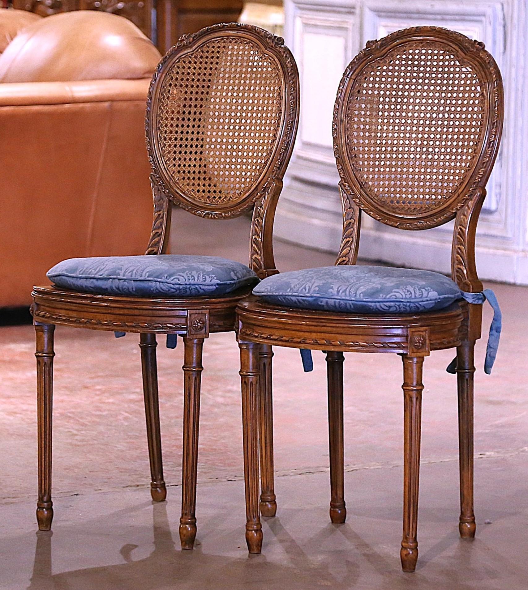 Crafted in France circa 1920, each side chair is finely carved and stands on classic elegant fluted Louis XVI-style legs, decorated with floral rosette medallions at the shoulder. The curved, arched back is crowned with hand-carved flower motifs at