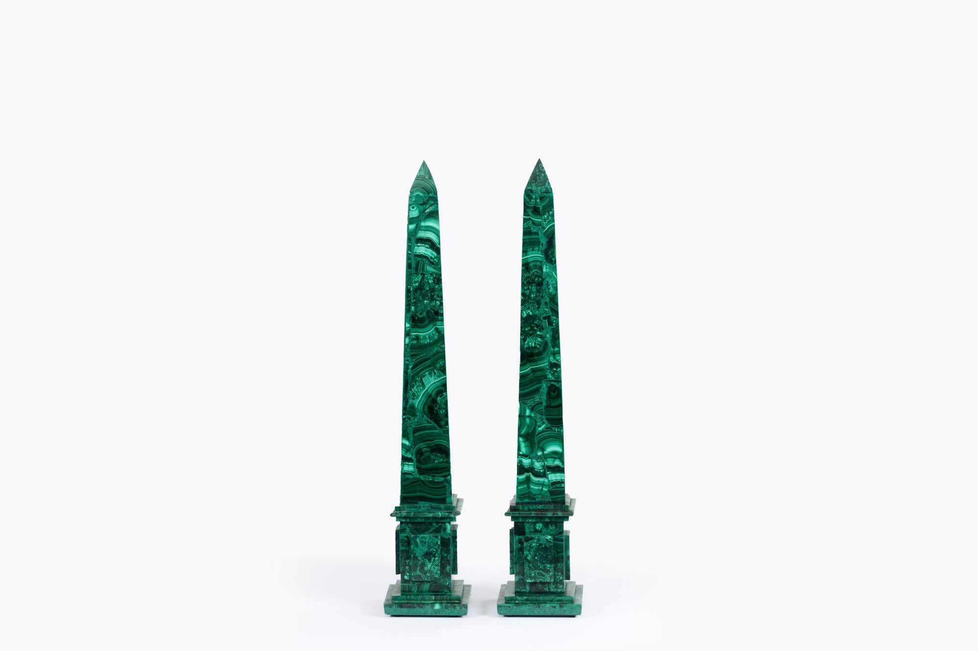 Pair early 20th Century Neoclassical-style decorative green malachite obelisks raised on square bases.

Malachite has been used as a gemstone and sculptural material for thousands of years and was one of the first ores used to produce copper metal.