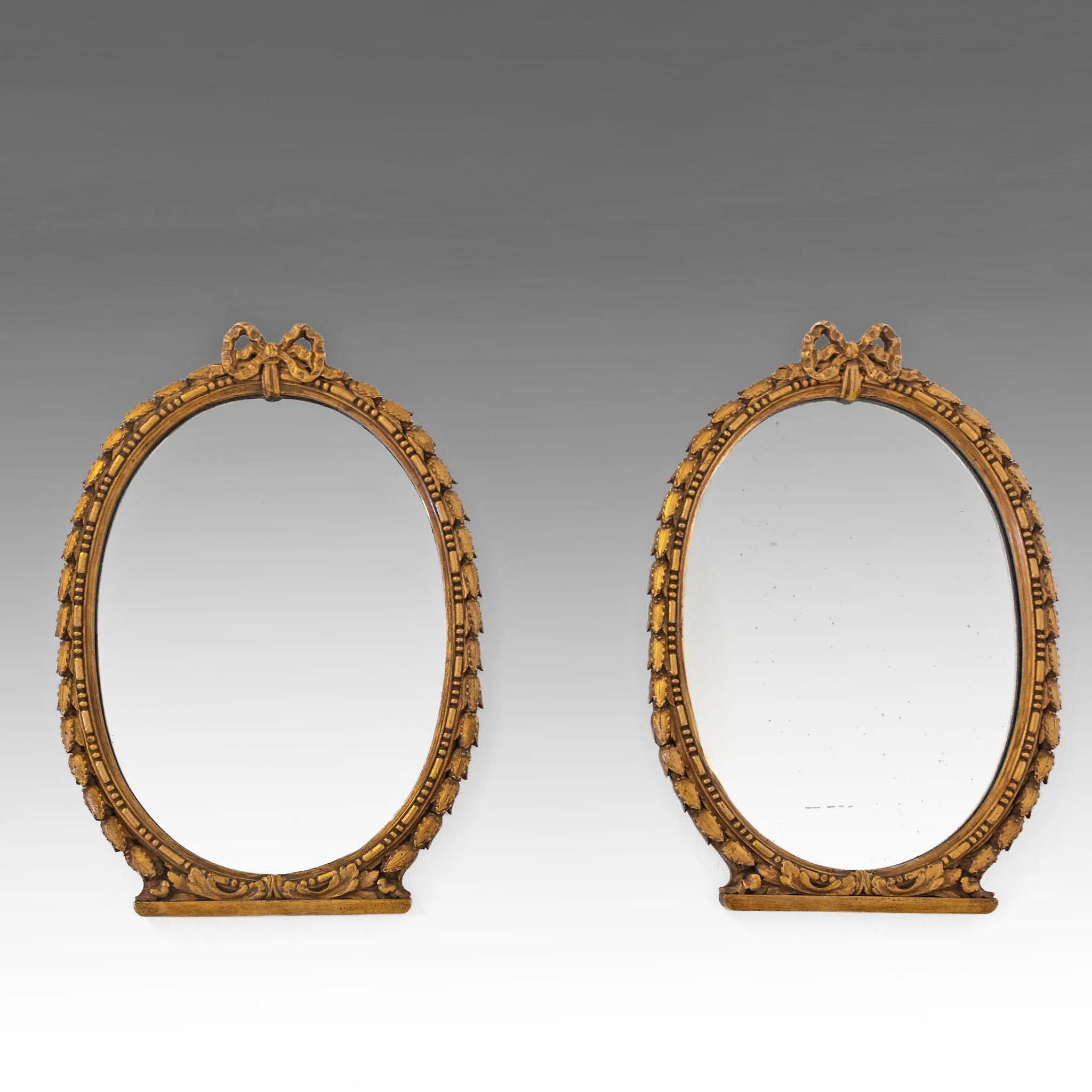 Pareja de pequeños espejos de pared ovalados de composición dorada de principios del siglo XX. Francés. Alrededor de 1900.

Los marcos decorativos tienen adornos de hojas y están rematados con una cinta arqueada.

Las placas de los espejos son