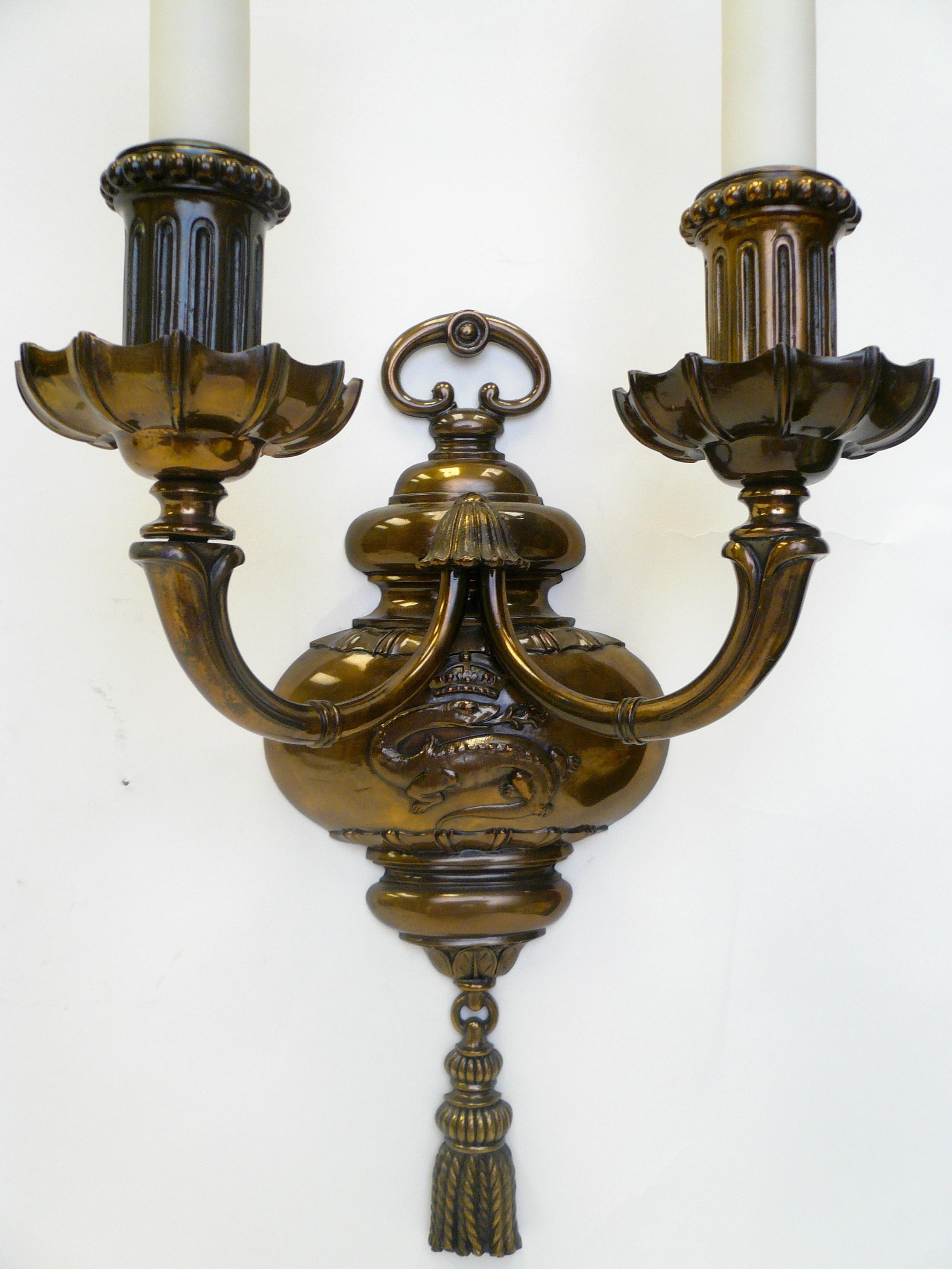 This pair of 'Old English' style sconces by renowned maker Edward F. Caldwell features dragons surmounted by noble crests, and terminate in finely detailed tassels.