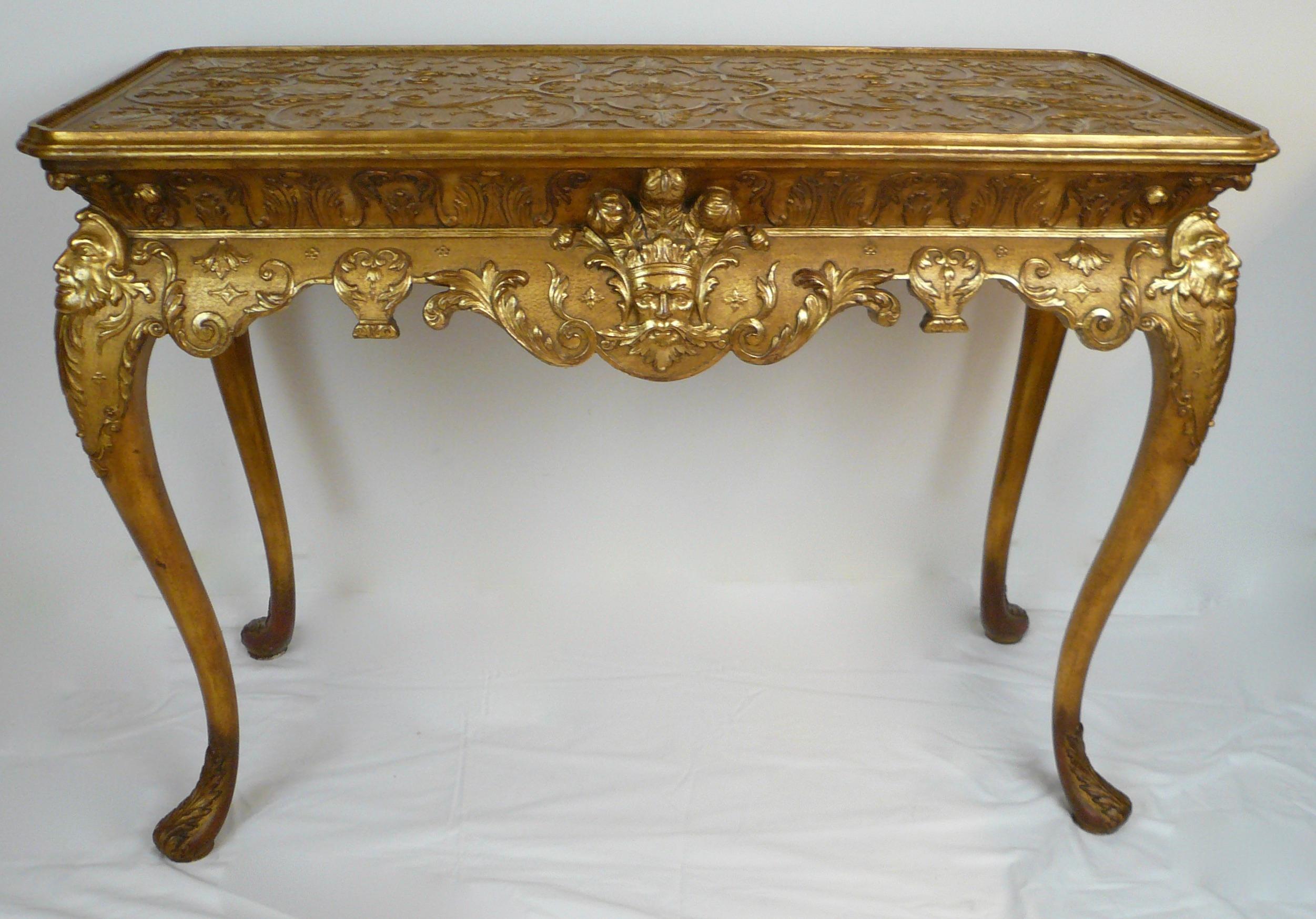 This impressive pair of gilt wood tables feature a carved frieze incorporating Prince of Wales plumes, leopard heads, and mask motifs. The cabriole legs with acanthus leaf carving terminate on pad feet.