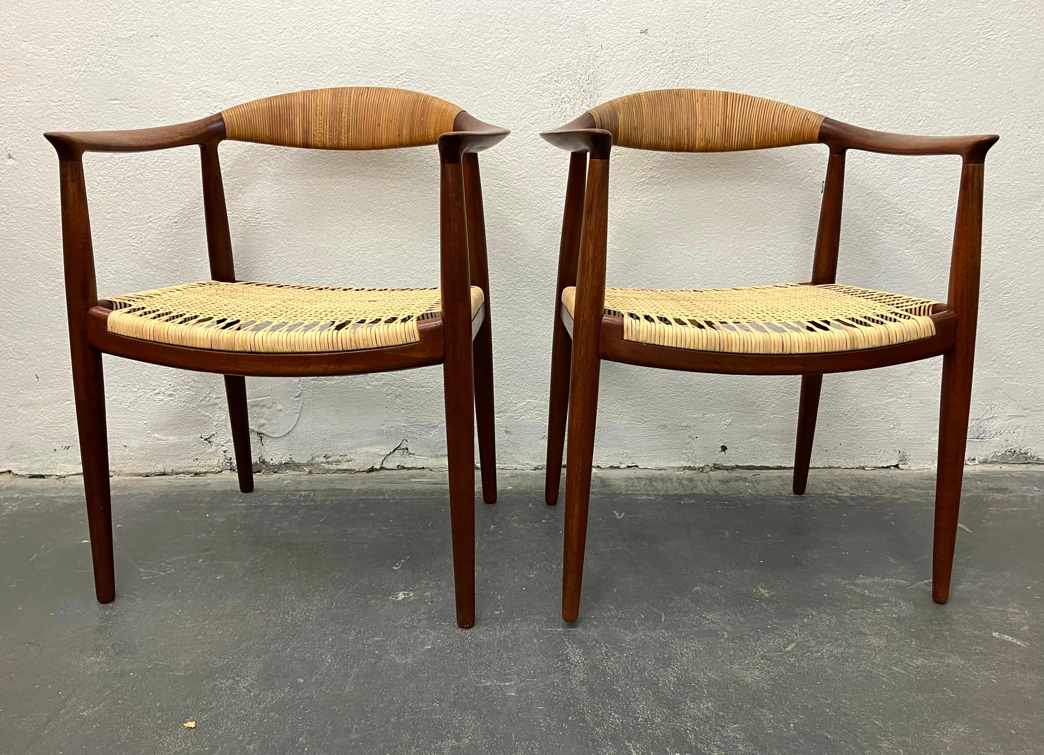 Classic  JH-501 teak arm chairs with cane seats. This is an especially beautiiful and early pair. The color of the wood and cane on the backs has aged so wonderfully that we have left it all original, beyond a light cleaning. The cane seats have