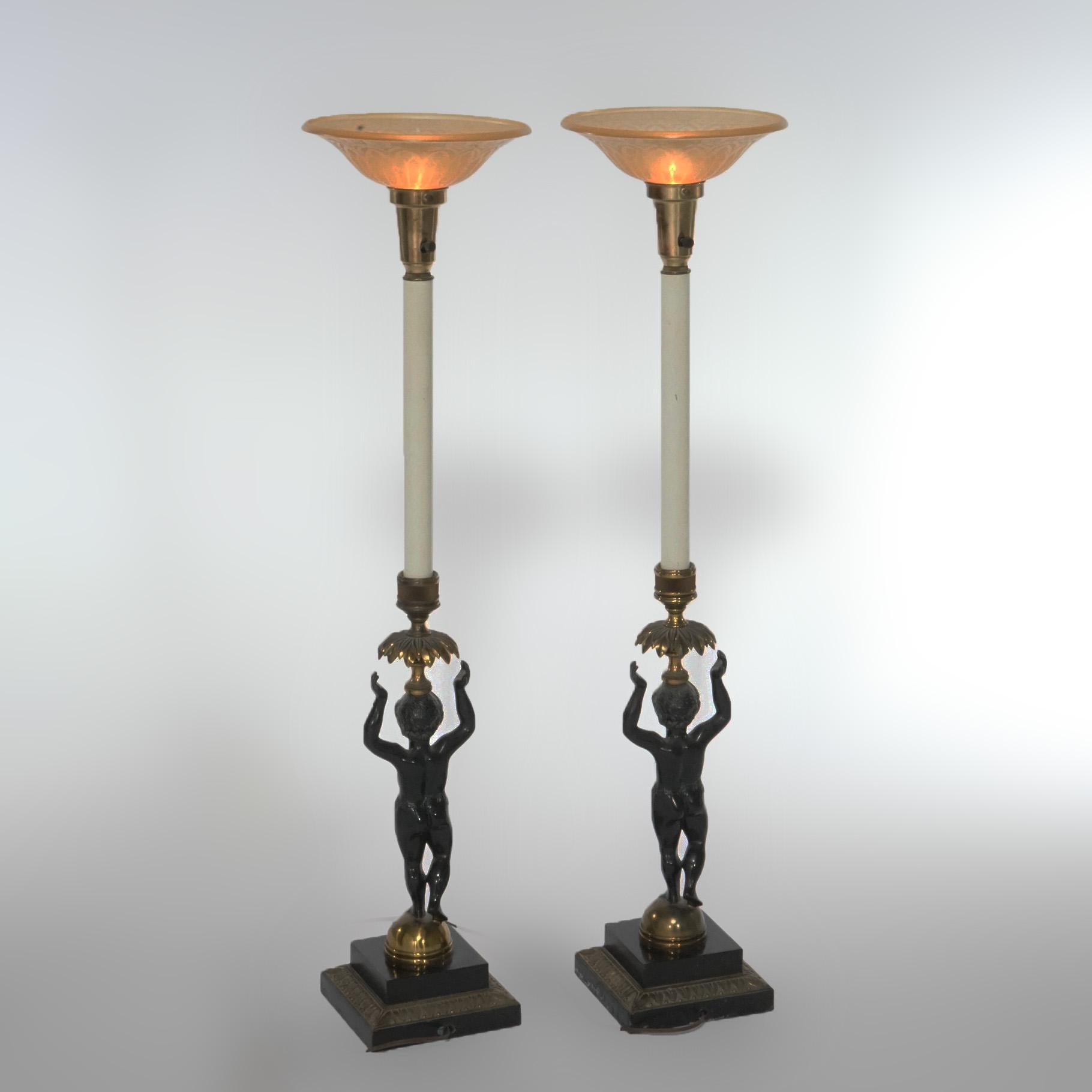 A pair of figural banquet lamps offer torchiere form with ebonized figural cherub column support, gilt foliate accents, 20th century.

Measures- 39''H x 7''W x 7''D.