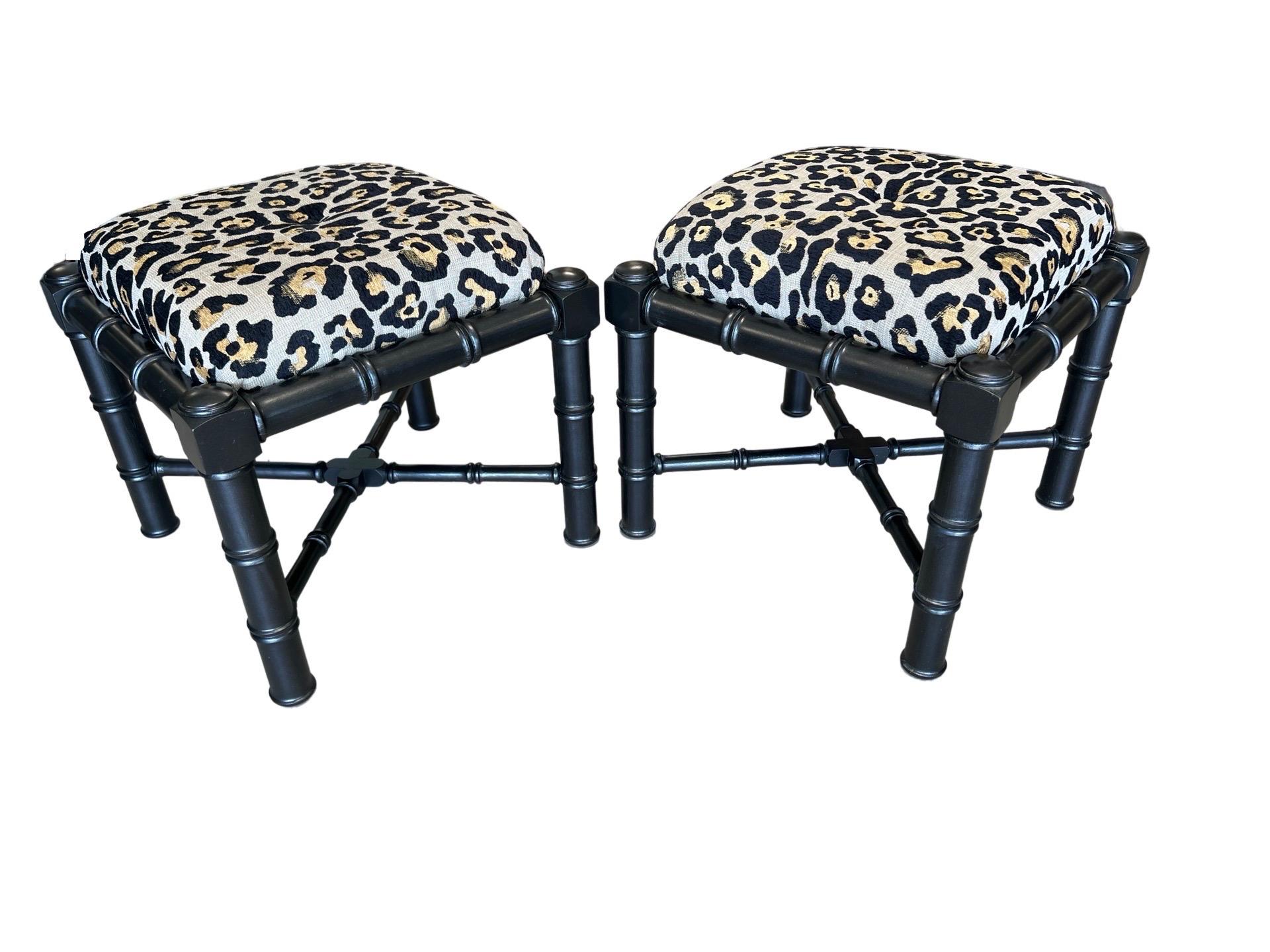 A pair of Vintage faux bamboo carved stools or footrests. Each with a black Ebonized finish to the body, x-cross support and upholstered in a leopard fabric. Unmarked.