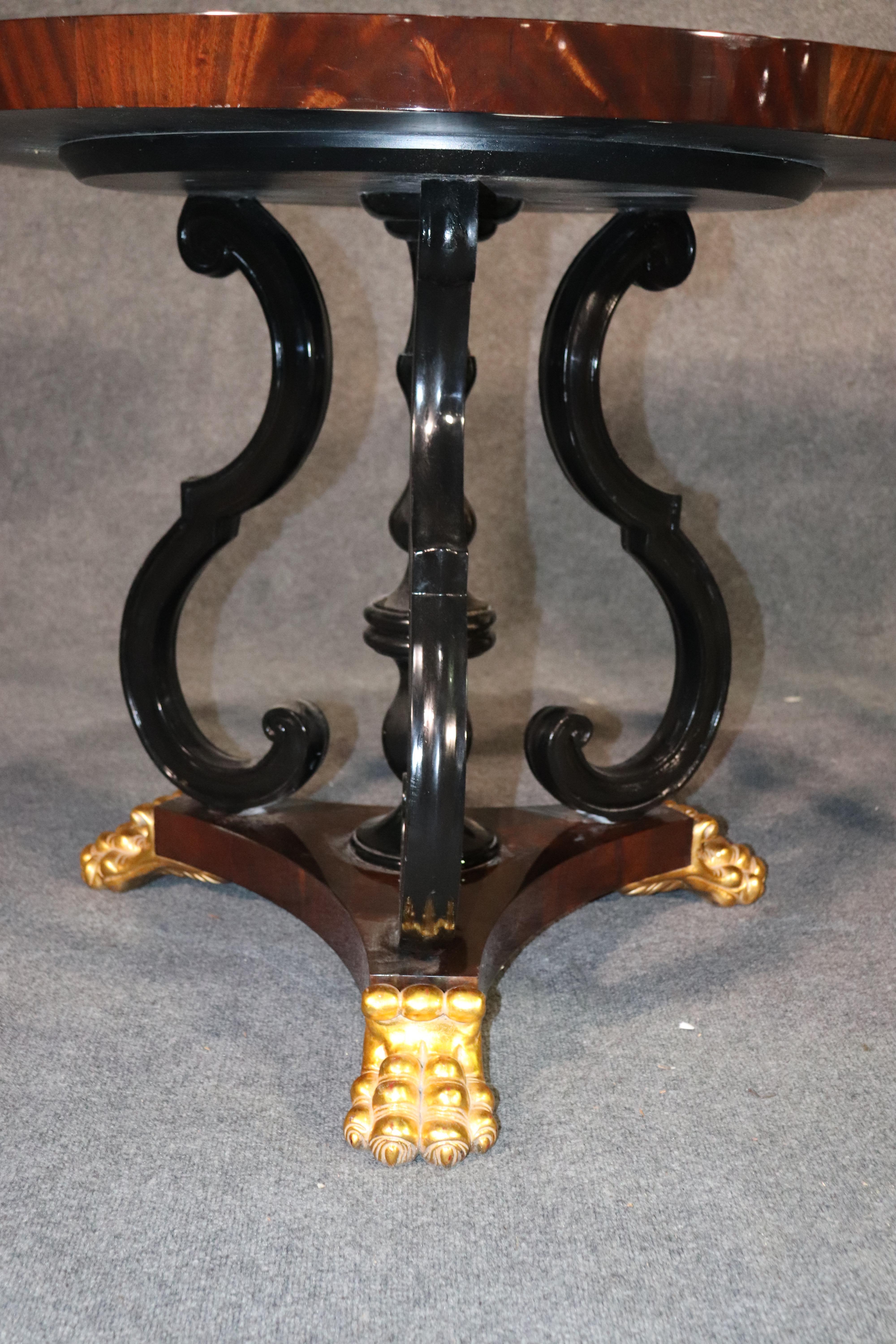 This is a beautiful pair of ebonized and genuine gold leafed tables. The tables are designed in the English Regency manner and have flame mahogany tops and black lacquered bases. They have very rich looking gilded paw feet and are rather large. The
