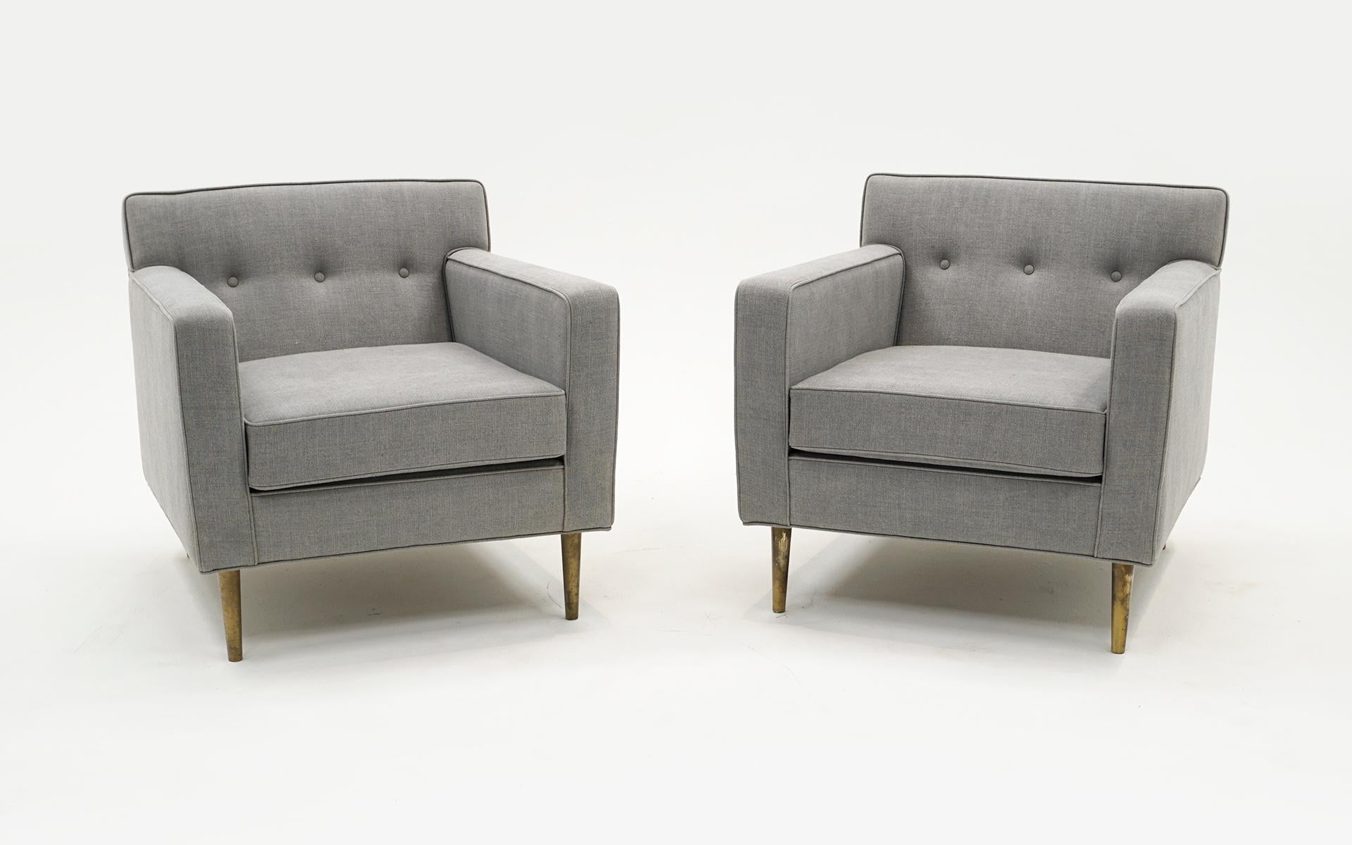 Beautiful pair of lounge chairs designed by Edward Wormley for Dunbar, 1948.  Expertly reupholstered in a light gray wool blend fabric.  The original legs are made of solid brass.  The upholstery is in excellent condition and the brass legs display
