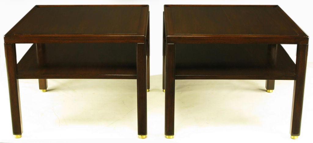 Pair of Edward Wormley for Dunbar Classic design two-tier end tables. Solid mahogany legs with raised panel and unexpected recessed brass disc feet. Solid mahogany top border with mahogany raised plateau top.