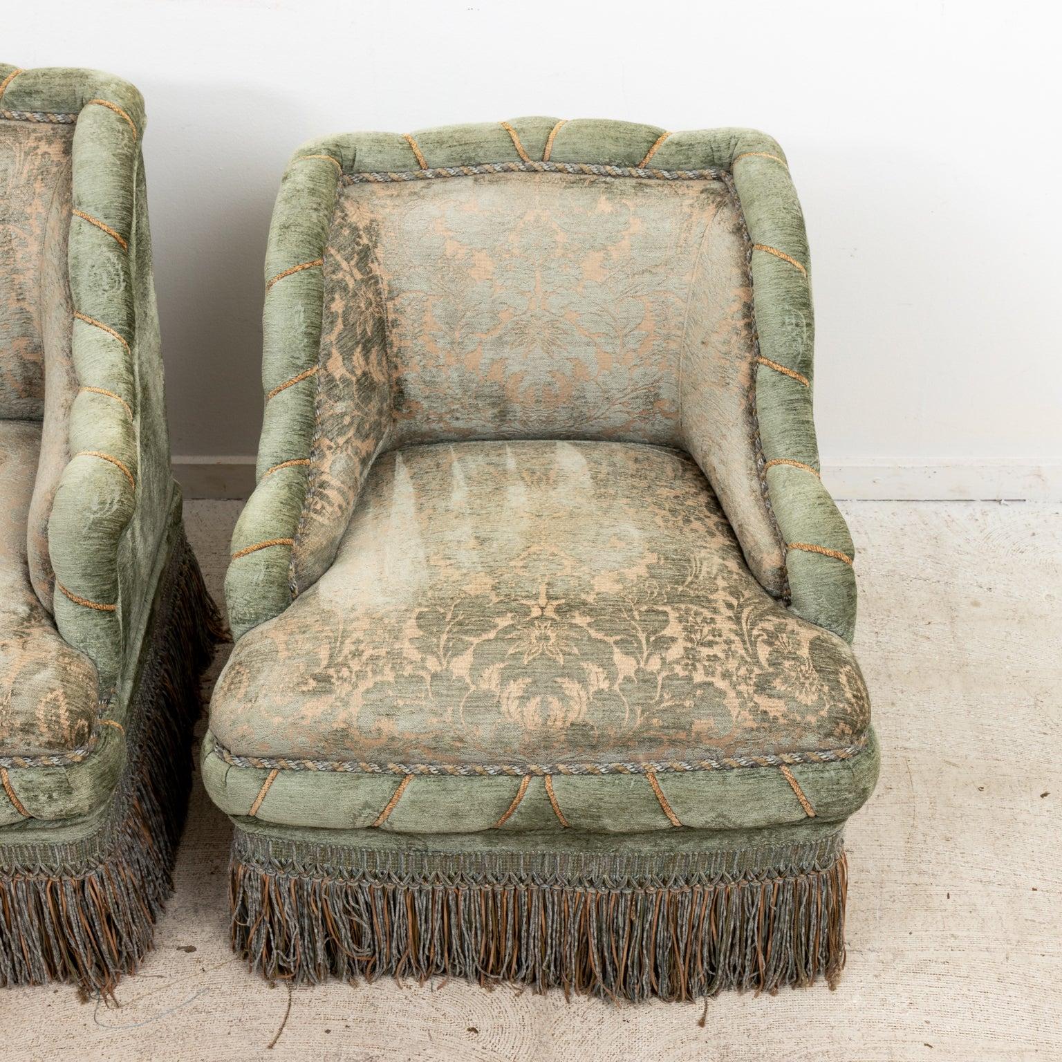 Pair Edwardian style damask upholstered armchairs with fringe trim. The Pair of chairs are not the same size. The larger chair is 29 inches wide, 30 inches high, 28 inches deep, 16 inches seat height. The smaller chair is 27 inches wide, 27.5 inches