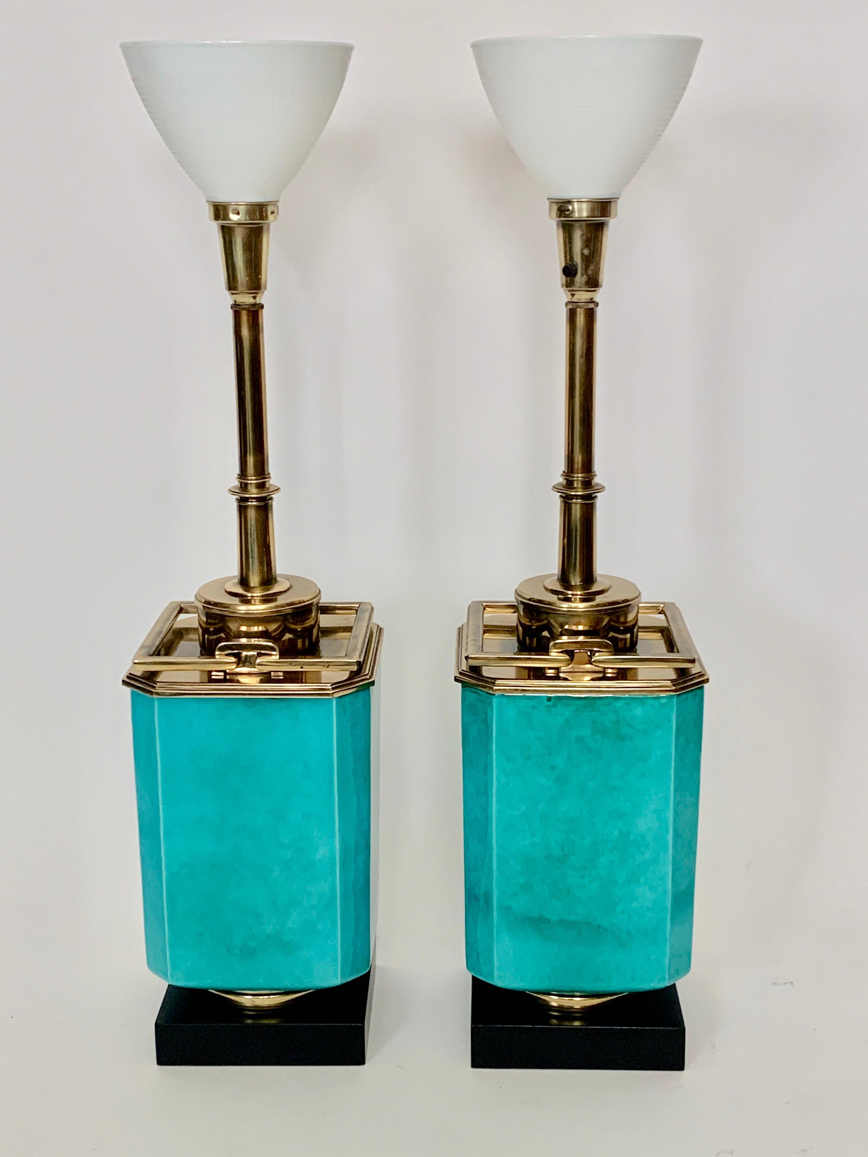 Substantial pair of Edwin Cole for Stiffel turquoise ceramic and bright brass table lamps, circa 1950. Featuring reflective Blue Green glazed ceramic bodies, solid bright brass hardware, working brass handles, square black enameled wood base and