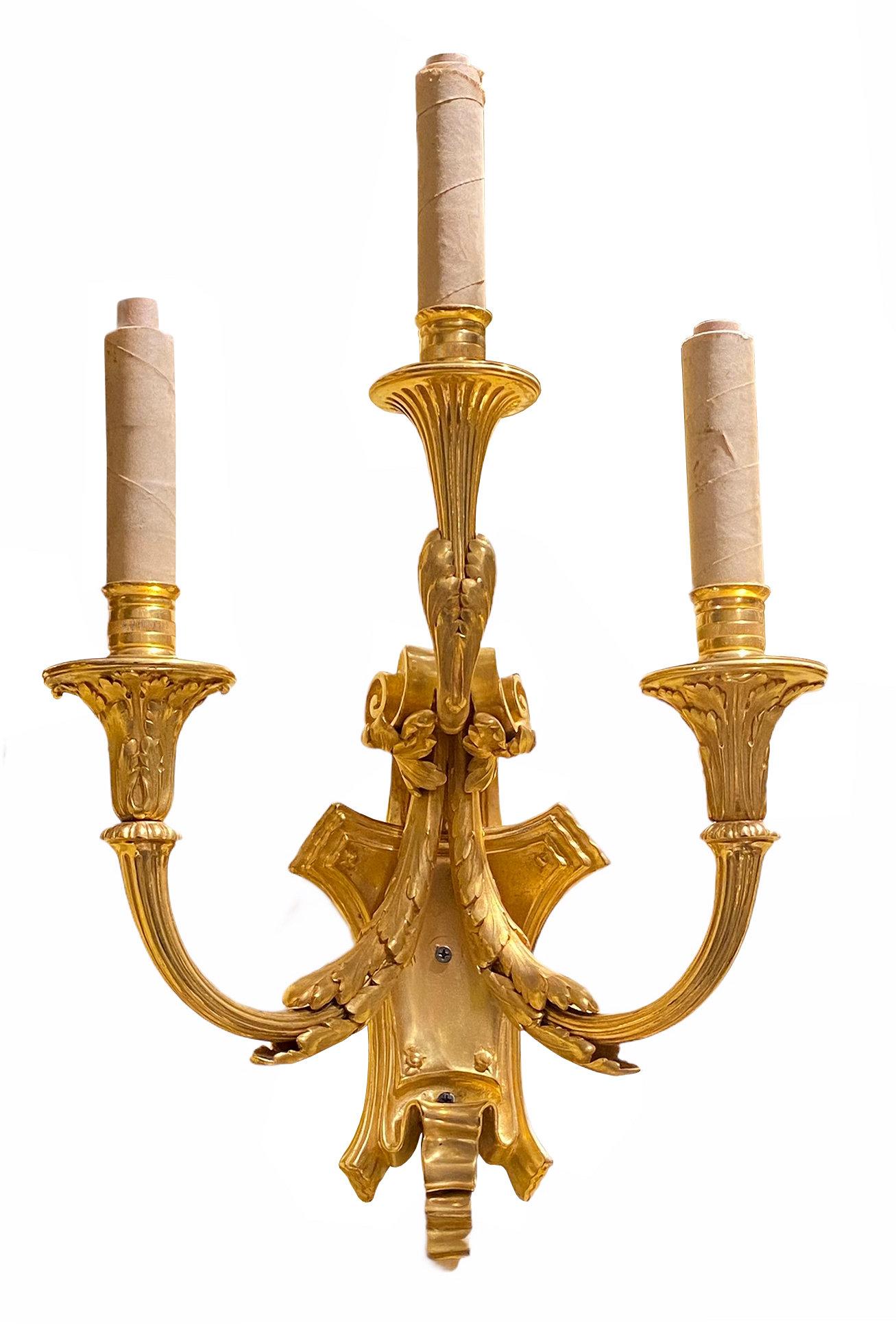 Pair American 19th century gilt bronze three-light sconces in the neoclassical Louis XVI style from Edward F. Caldwell, exhibiting the finest casting, finishing and gilding. With impressed mark of the maker on rear and original sockets with white