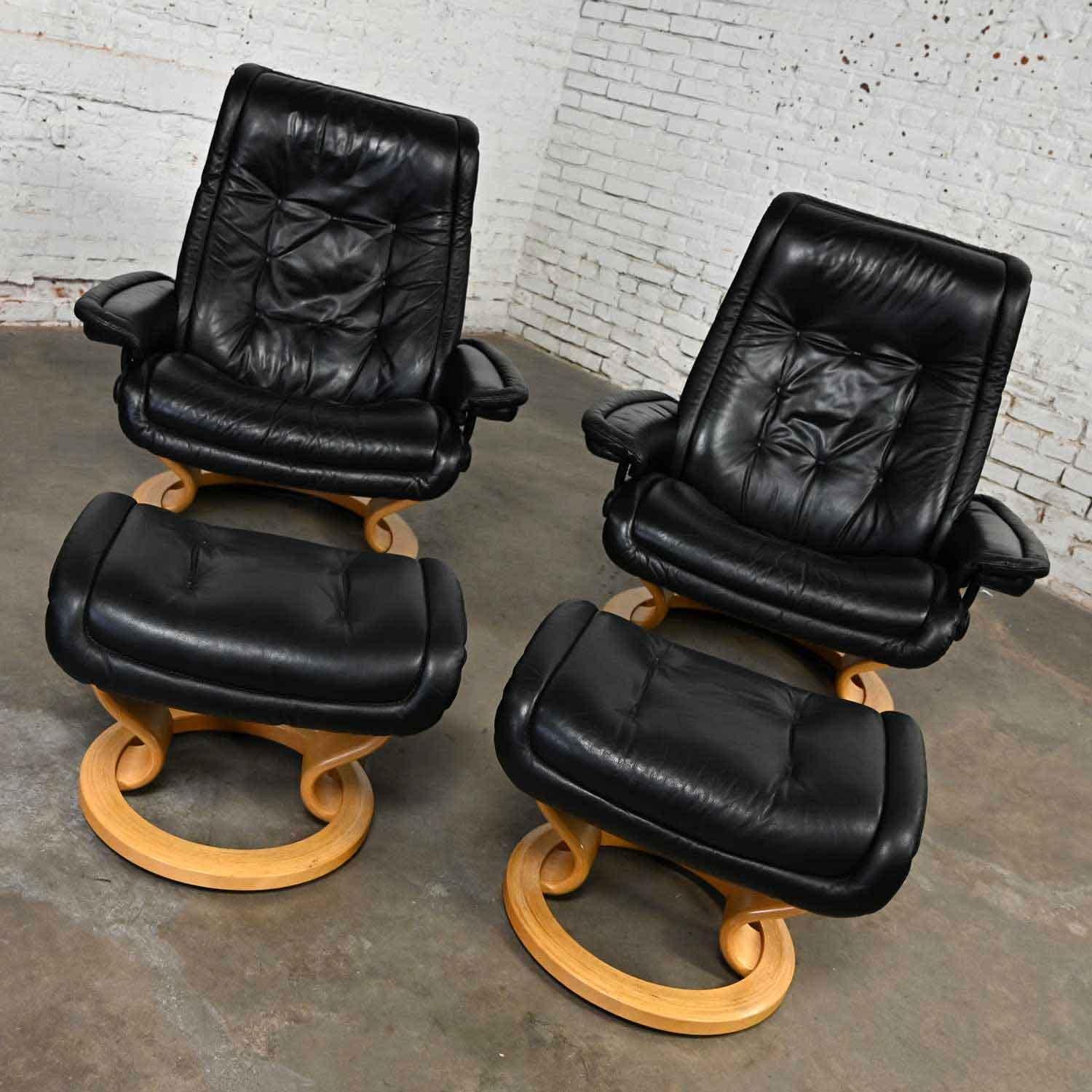 Handsome vintage Ekornes Stressless Royal Recliner black leather lounge chairs with wood bases, a pair. Beautiful condition, keeping in mind that this is vintage and not new so will have signs of use and wear. We have cleaned, polished, and