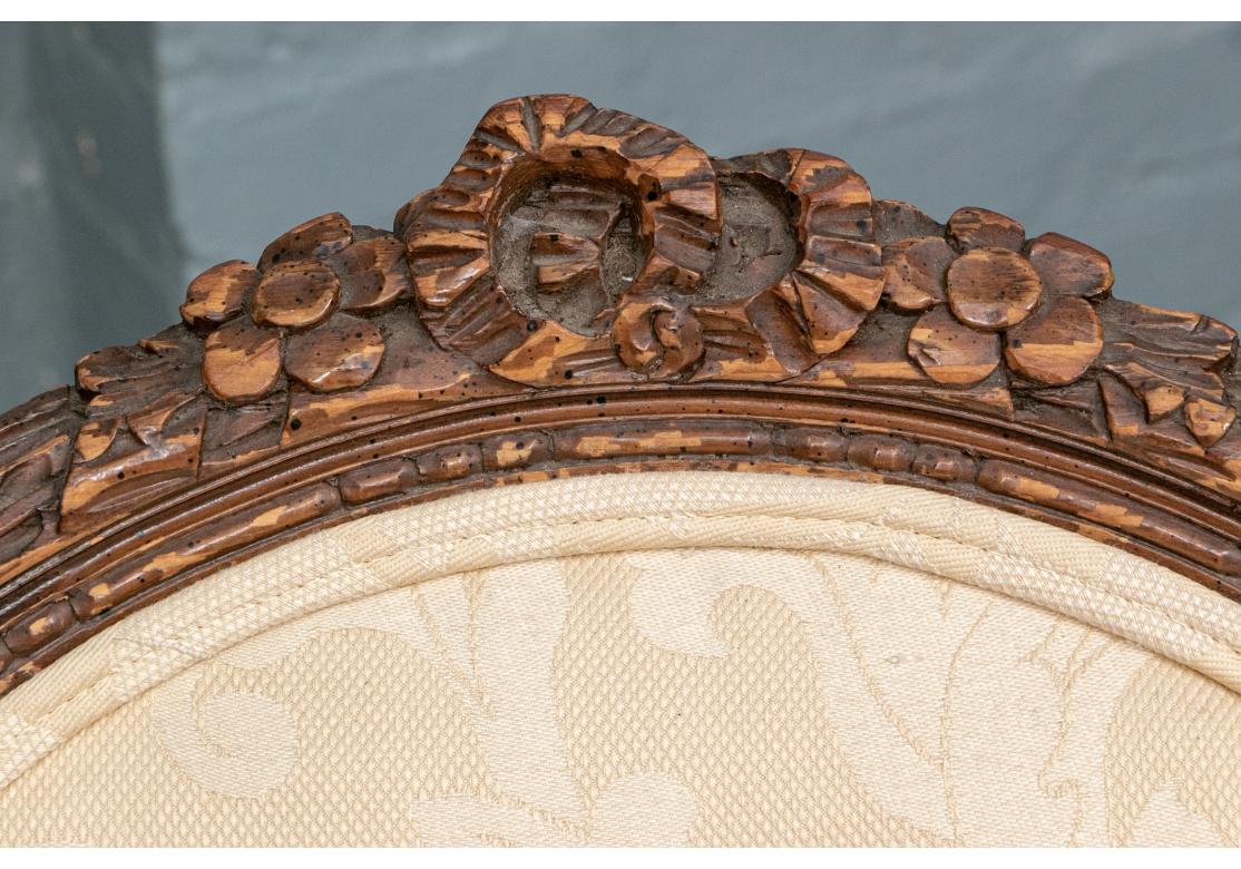 Ein elegantes Paar Stühle im Stil Louis XVI aus der ersten Hälfte des 20. Jahrhunderts. In einer dunklen Beize, die ovalen Rückseiten mit geschnitzten floralen Wappenleiste mit Band Wappen, und Band Twist Frames insgesamt. Blattförmig geschwungene
