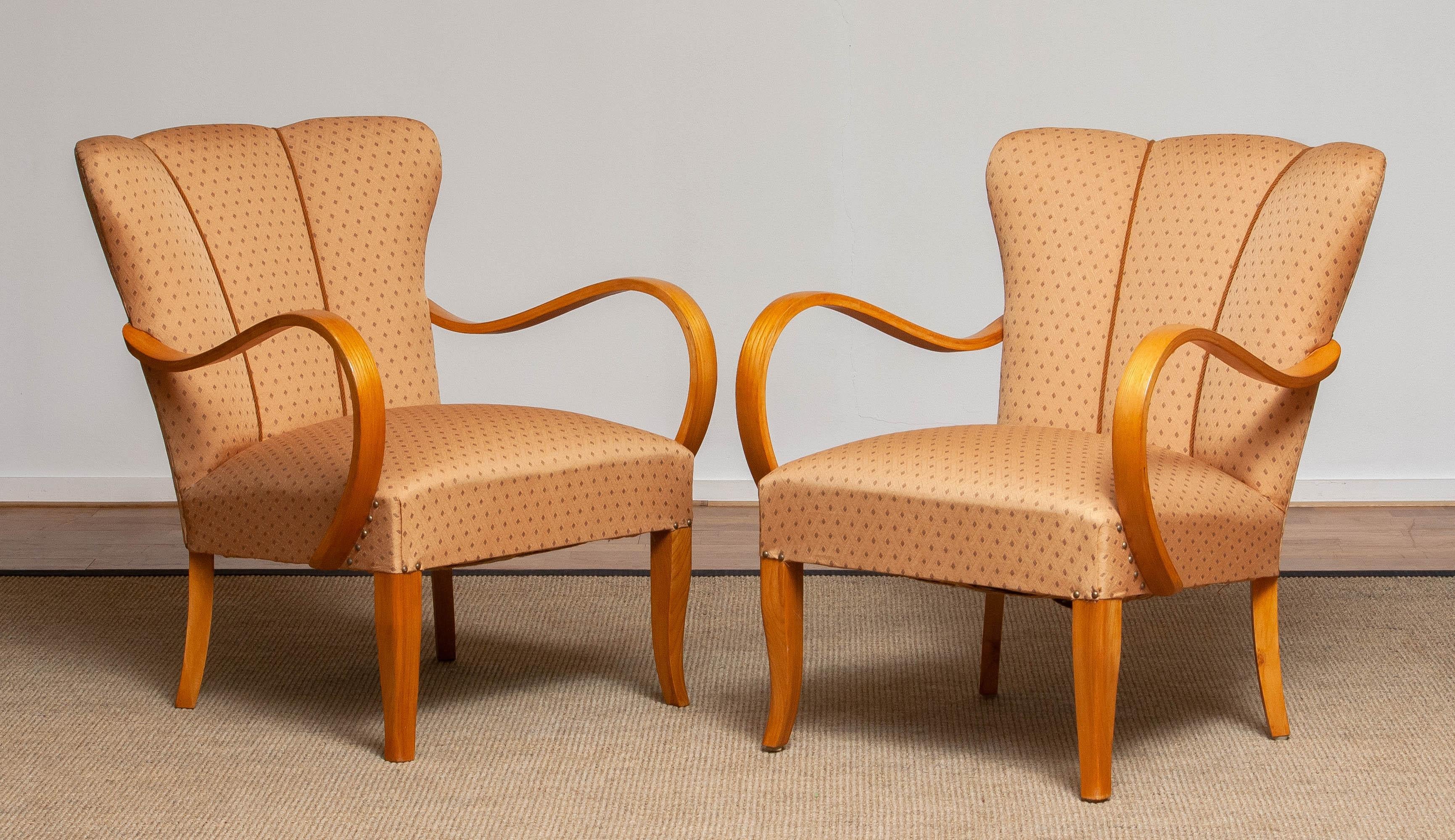 Precioso par de sillones románticos de los años 40 con elegantes reposabrazos curvados de madera curvada de olmo. Los reposabrazos de olmo tienen un precioso veteado dorado que llama absolutamente la atención. Tejido jacquard ocre en buen estado y