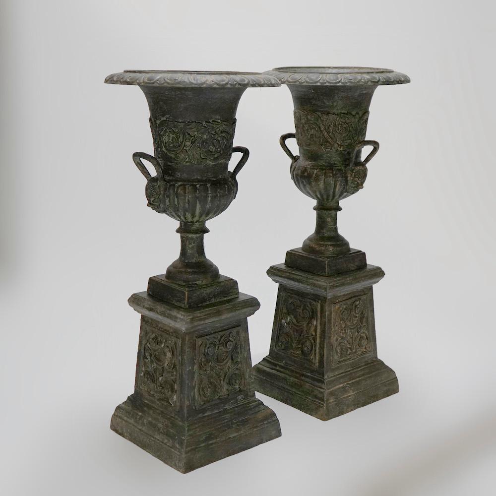 A pair of Classical garden urns offer cast iron construction with egg and dart rim.
Over floral embossed vessel with melon form base, flanking handles and raised matching embossed bases, 20th century.

Measures- 40.5''H x 18.5''W x 18.5''D.