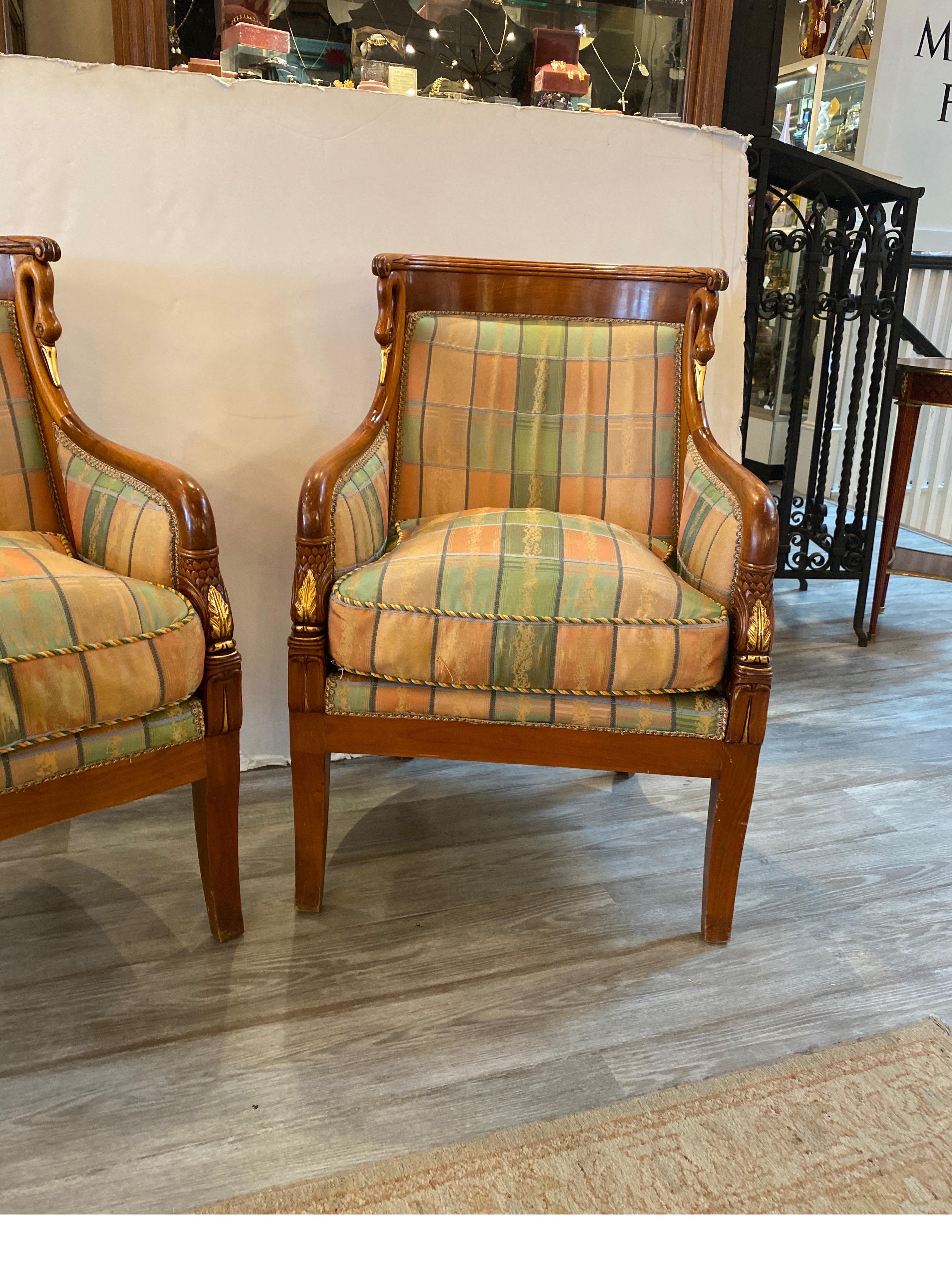 A Pair of Empire style fruitwood hand carved rounded back chairs with swan and dolphin motif with gilt accents. The rounded backs, with separate seat cushions. The fabric is slightly worn and would probably be best to reupholster.