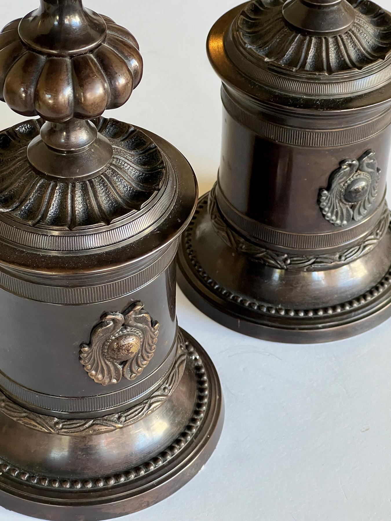ogni pesante portacandele è sormontato da un portacandele poco profondo con labbro svasato, sollevato su un sostegno a forma di gadroon sopra un anello di foglie stilizzate; il tutto su una base cilindrica ornata da borchie applicate fiancheggiate
