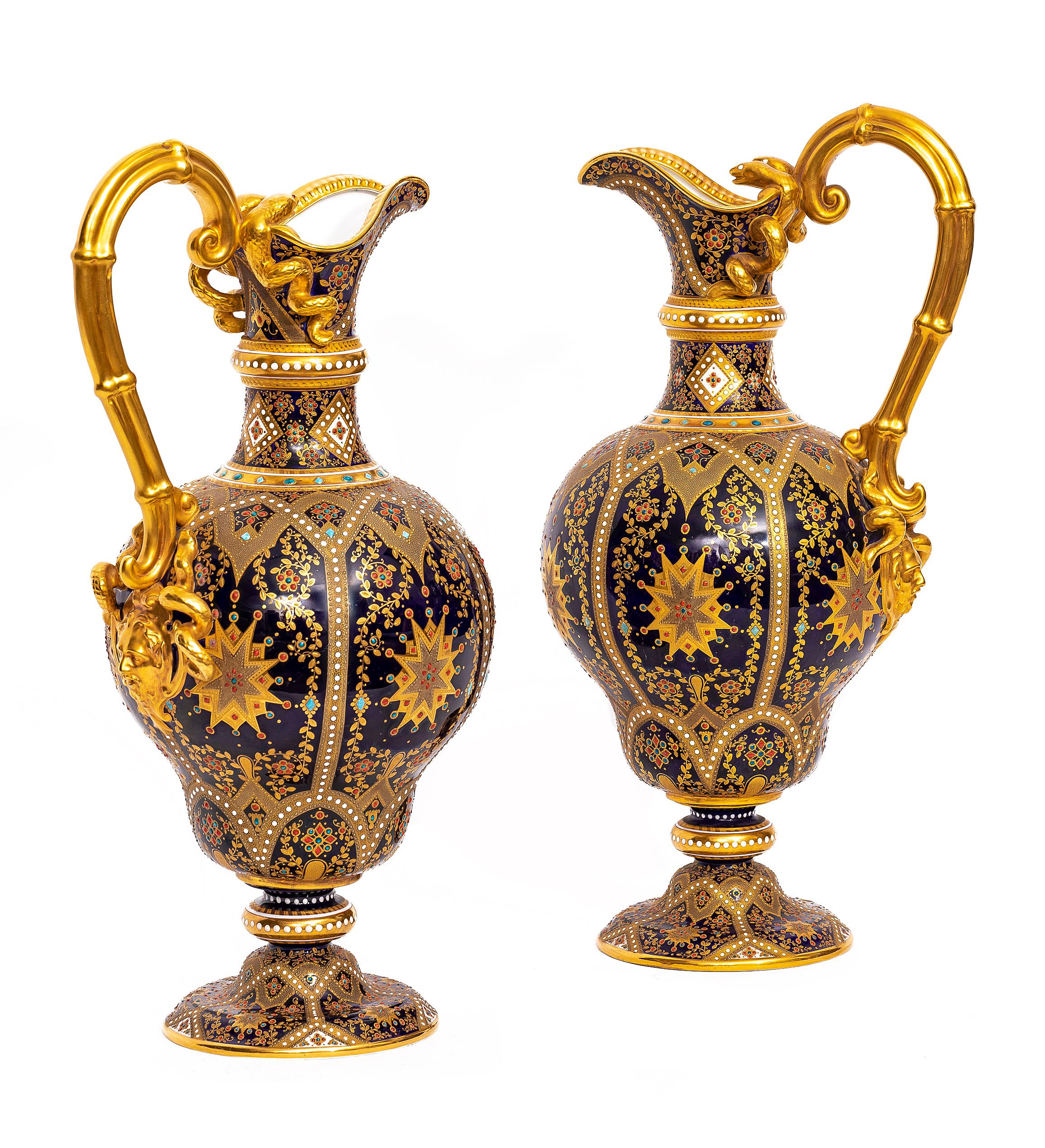 A Very Rare Pair of English 19th Century Cobalt Blue Ground Jeweled and Gilt Double snake Handle Ewers by Copeland.  Each ewer consists of a cobalt blue ground, featuring a bulbous body tapering to a narrow neck and a wide, flaring spout. Each ewer