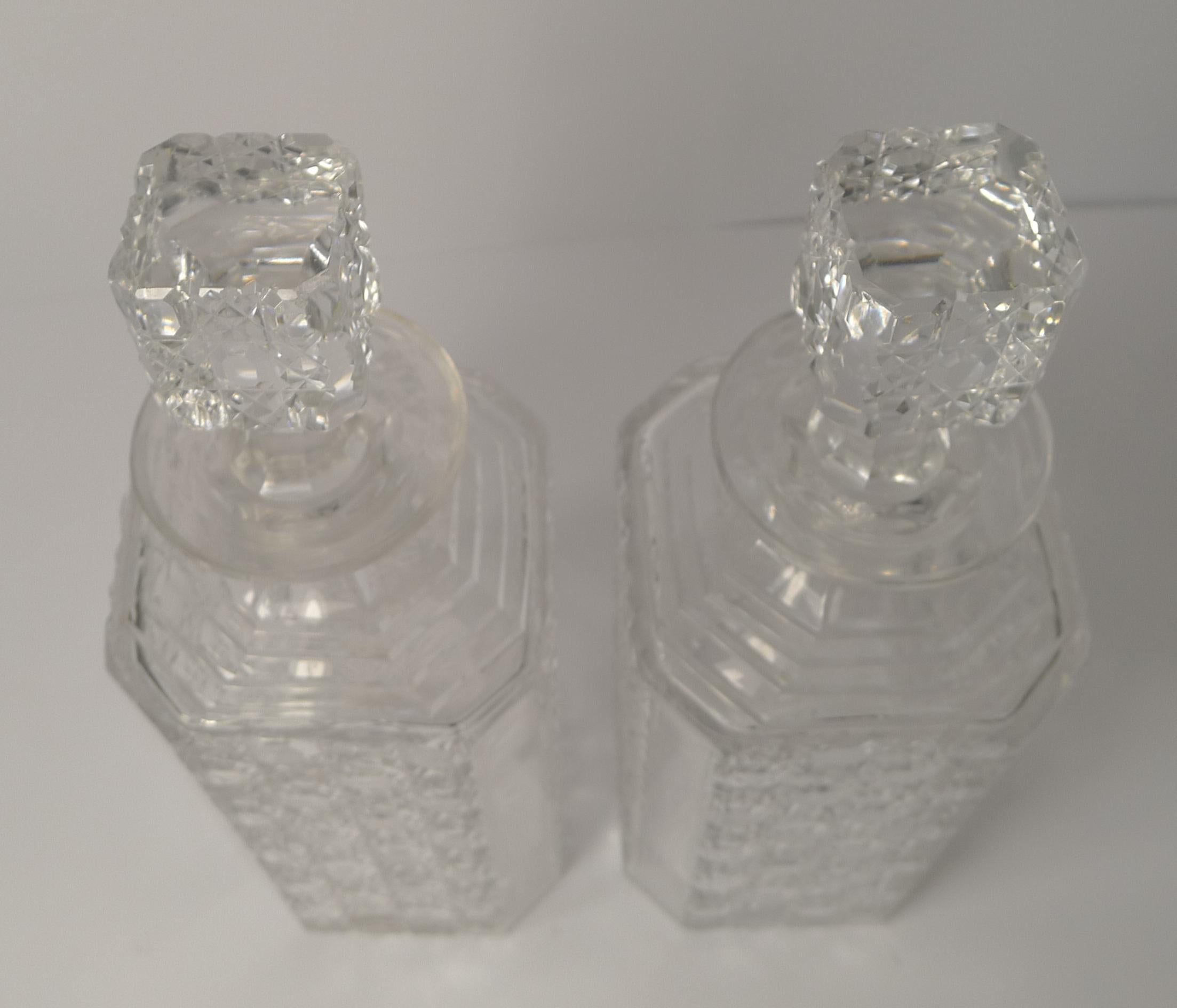 A lovely pair of decanters, an Art Deco take on a more traditional hobnail cut decanter. This pair has stepped cut shoulders and square stoppers.

Dating to circa 1920-1930, they remain in excellent condition measuring 3 1/4