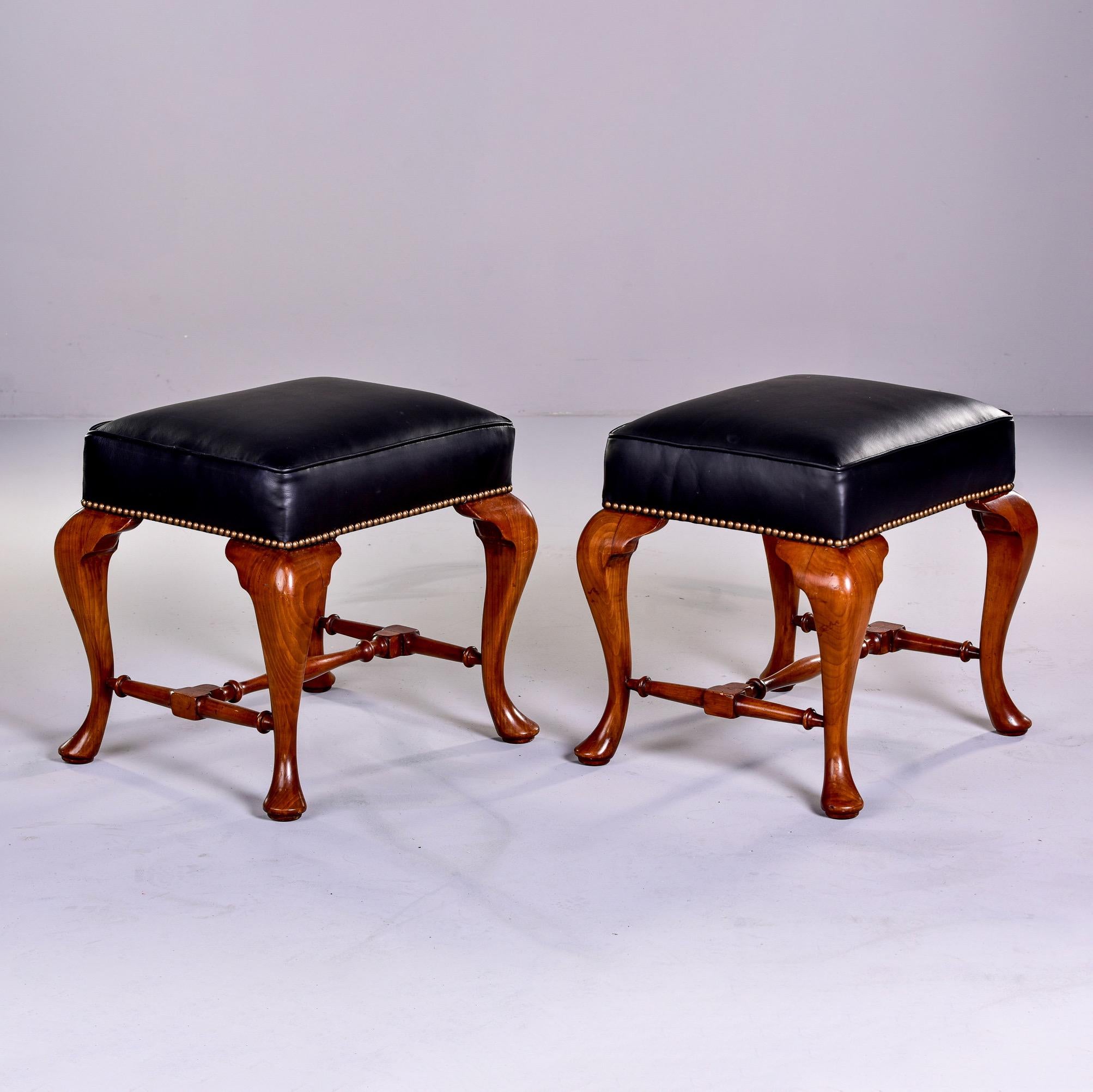 Circa 1920s pair of English stools with cherry frames, dramatic cabriole legs and new black leather upholstery with brass nail heads along bottom edge. Unknown maker. Sold and priced as a pair.
 