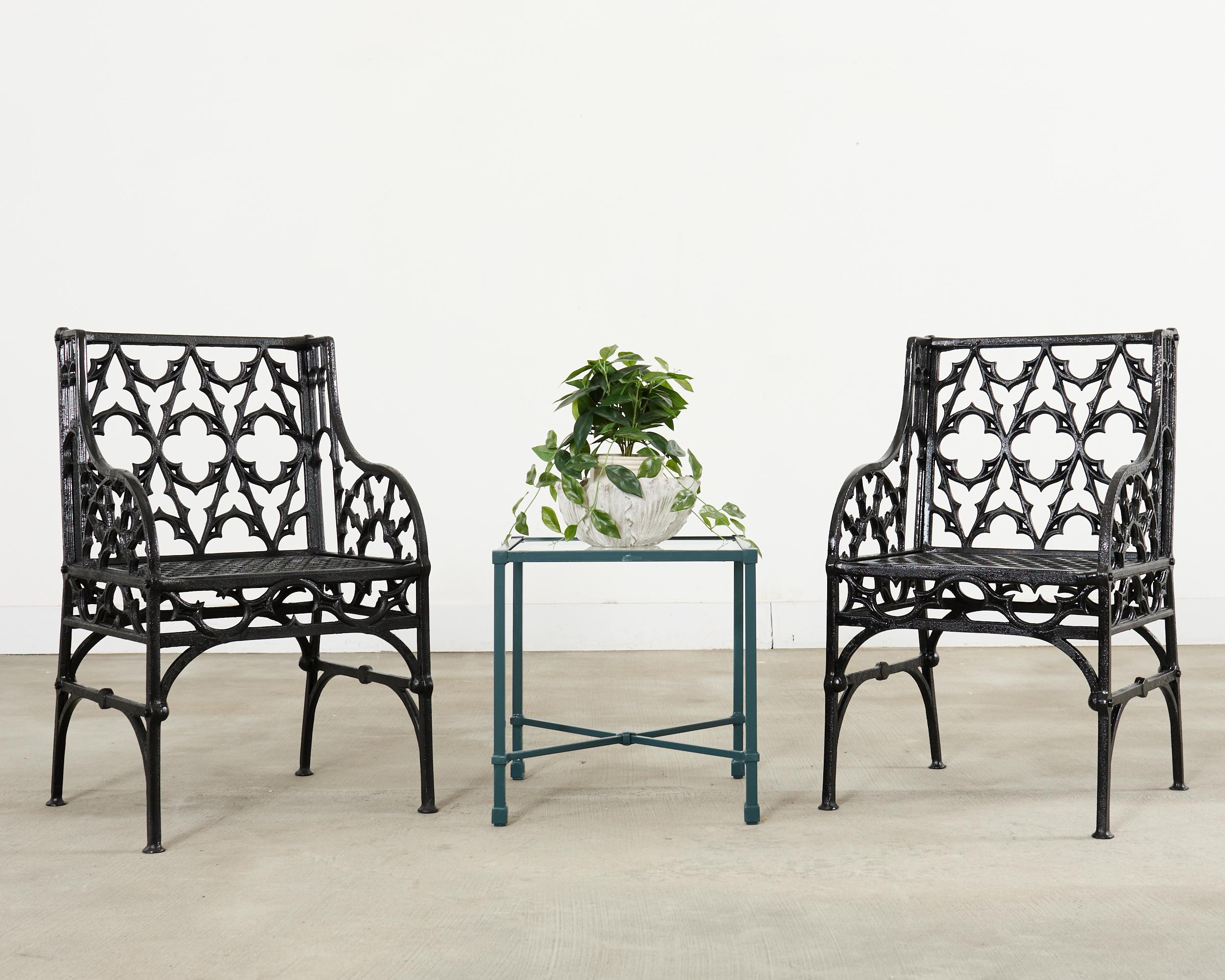 Rare pair of opulent English Gothic revival style garden armchairs made in the manner of Coalbrookdale Foundry. The frames are heavy and solid featuring gothic tracery and quatrefoil designs on the backrest. The gracefully curved arms enclosing