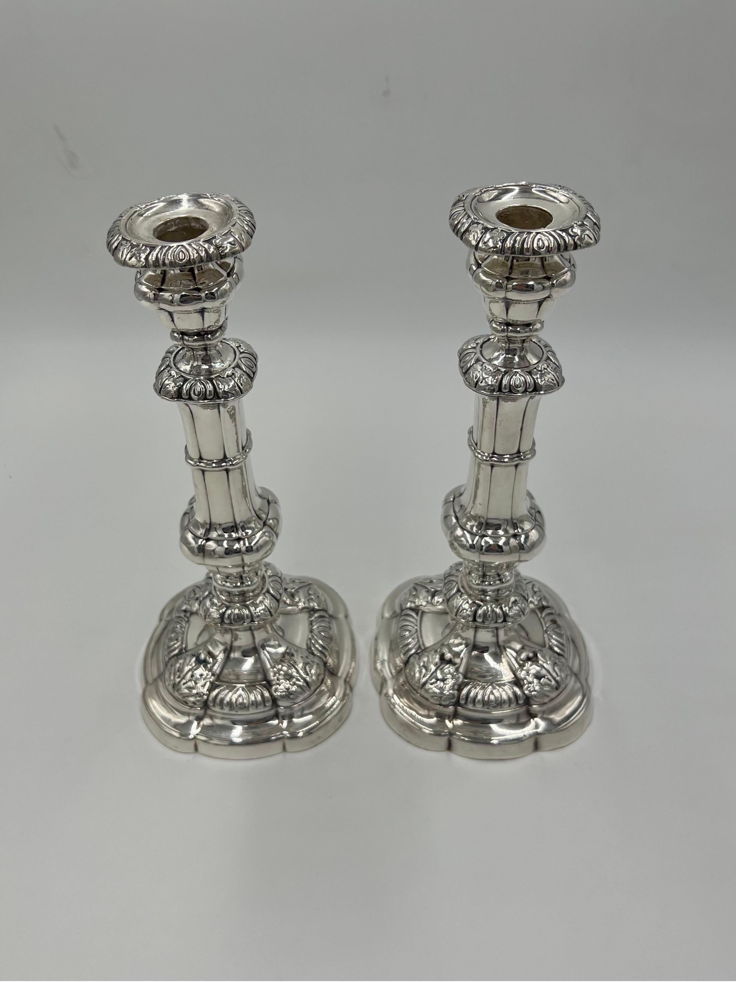 A pair of George II period sterling silver candlesticks. The tops of each with removable holders, gadrooning to edges, fluted columns supports to center stems and banding accents. The stems terminate into a scalloped edge base accented by acanthus